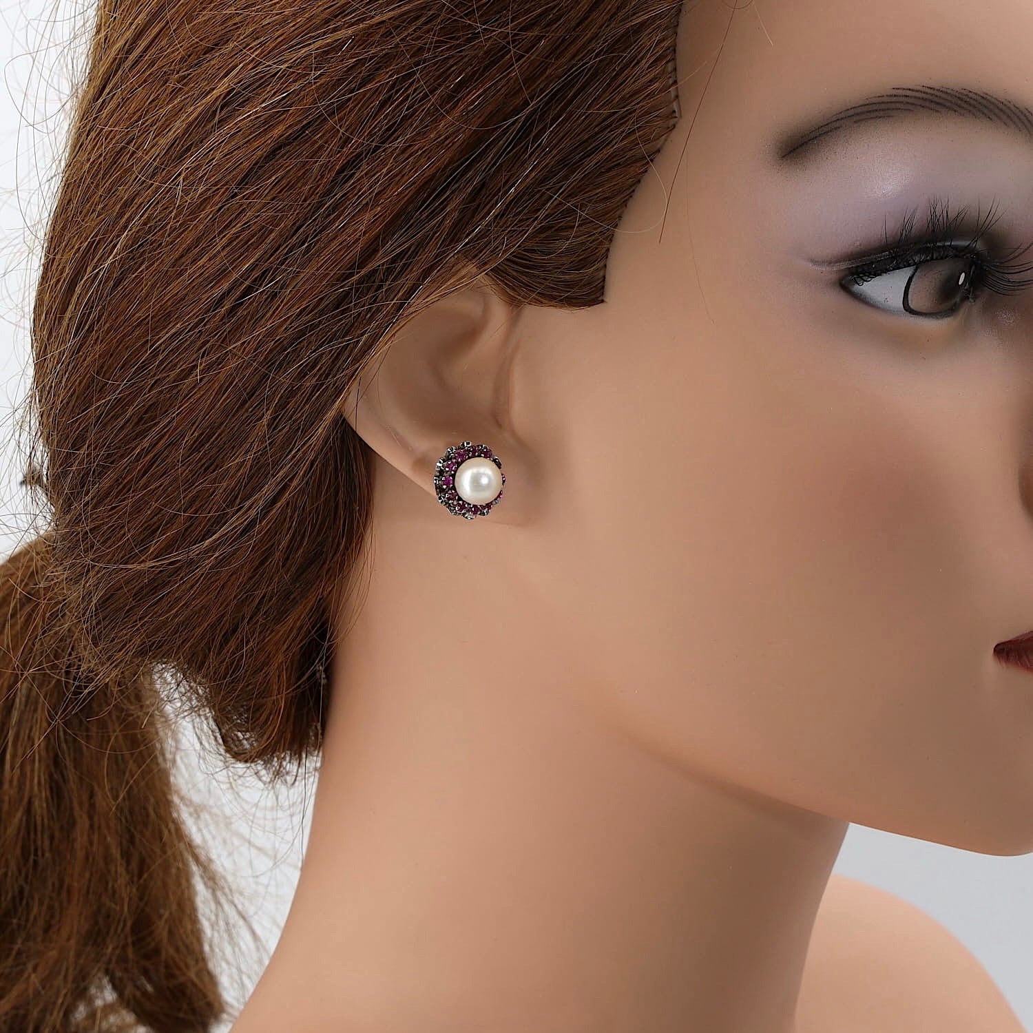 Stud earrings in 750 white gold with one each cultured pearl and rubies, individually on a doll's ear