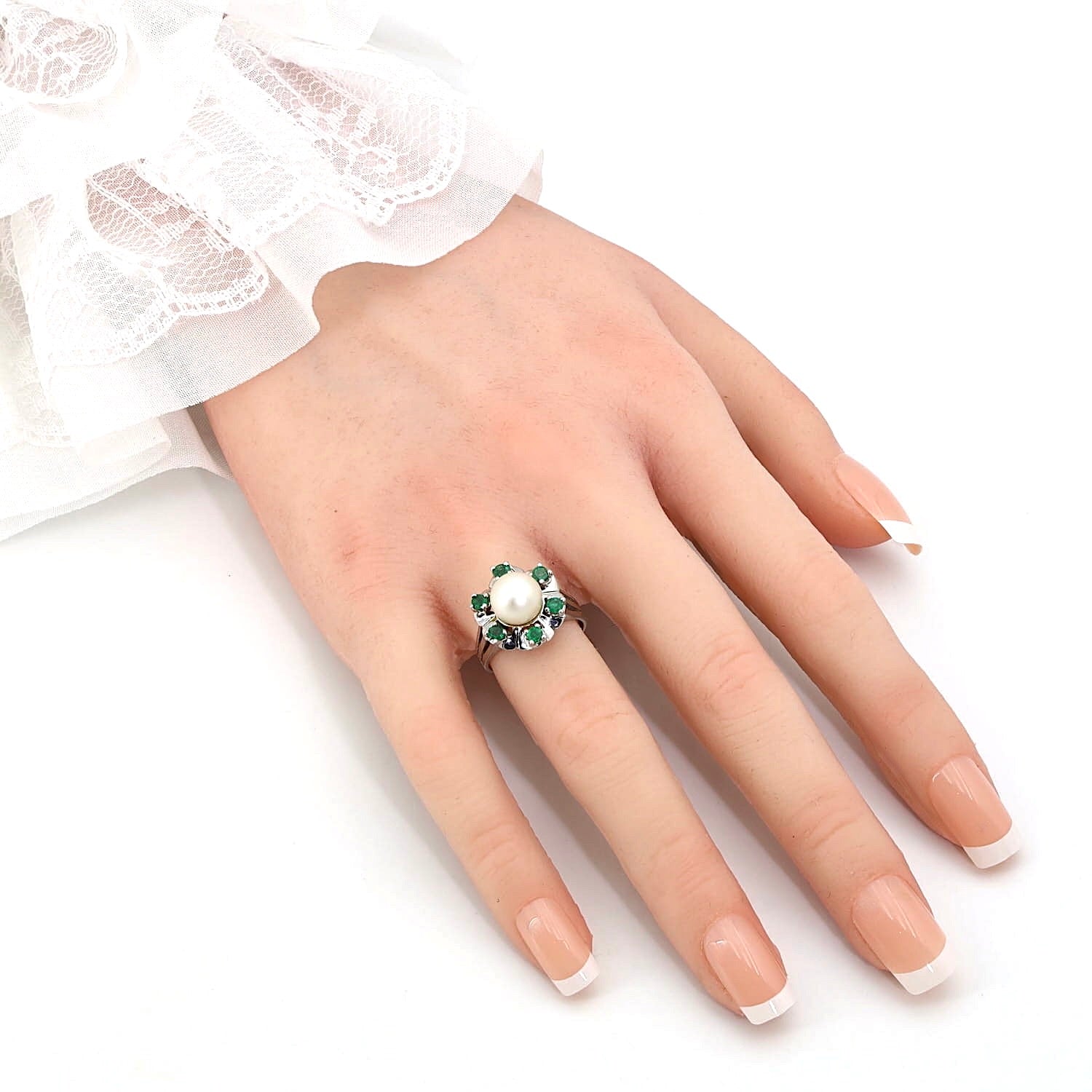 Ring in 585er Weißgold mit einer Akoya-Zuchtperle und Smaragden, an der künstlichen Hand