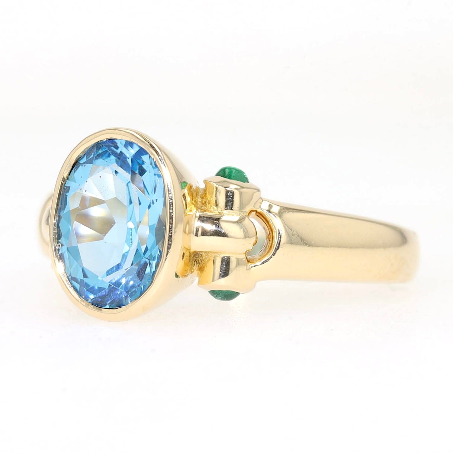 Ring in 750er Gelbgold mit einem blauen Topas und Smaragden, liegend links gedreht