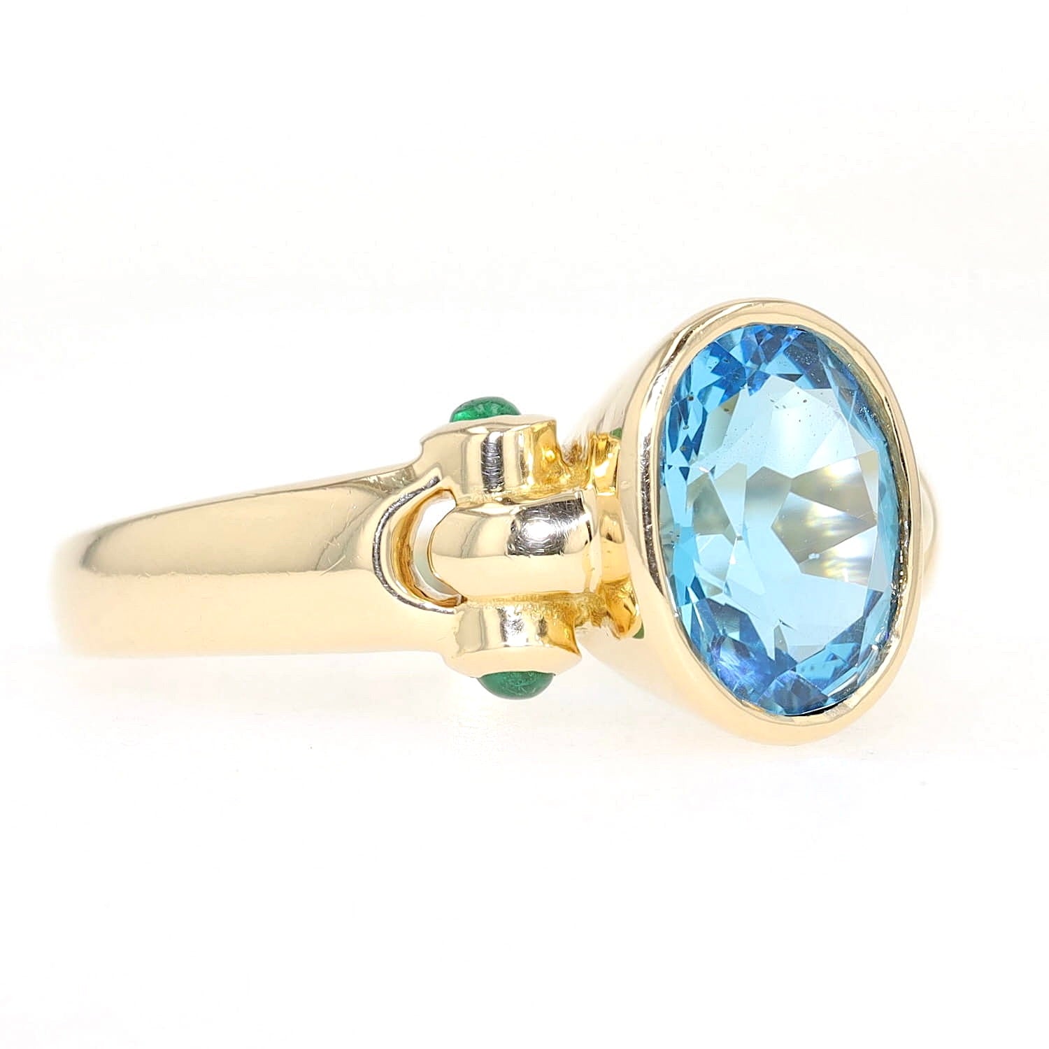 Ring in 750er Gelbgold mit einem blauen Topas und Smaragden, liegend rechts gedreht