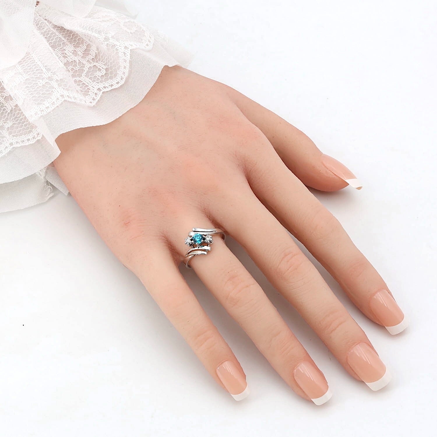 Ring in 585er Weißgold mit einem natürlichen blauen Zirkon und Diamanten, an einer künstlichen Hand