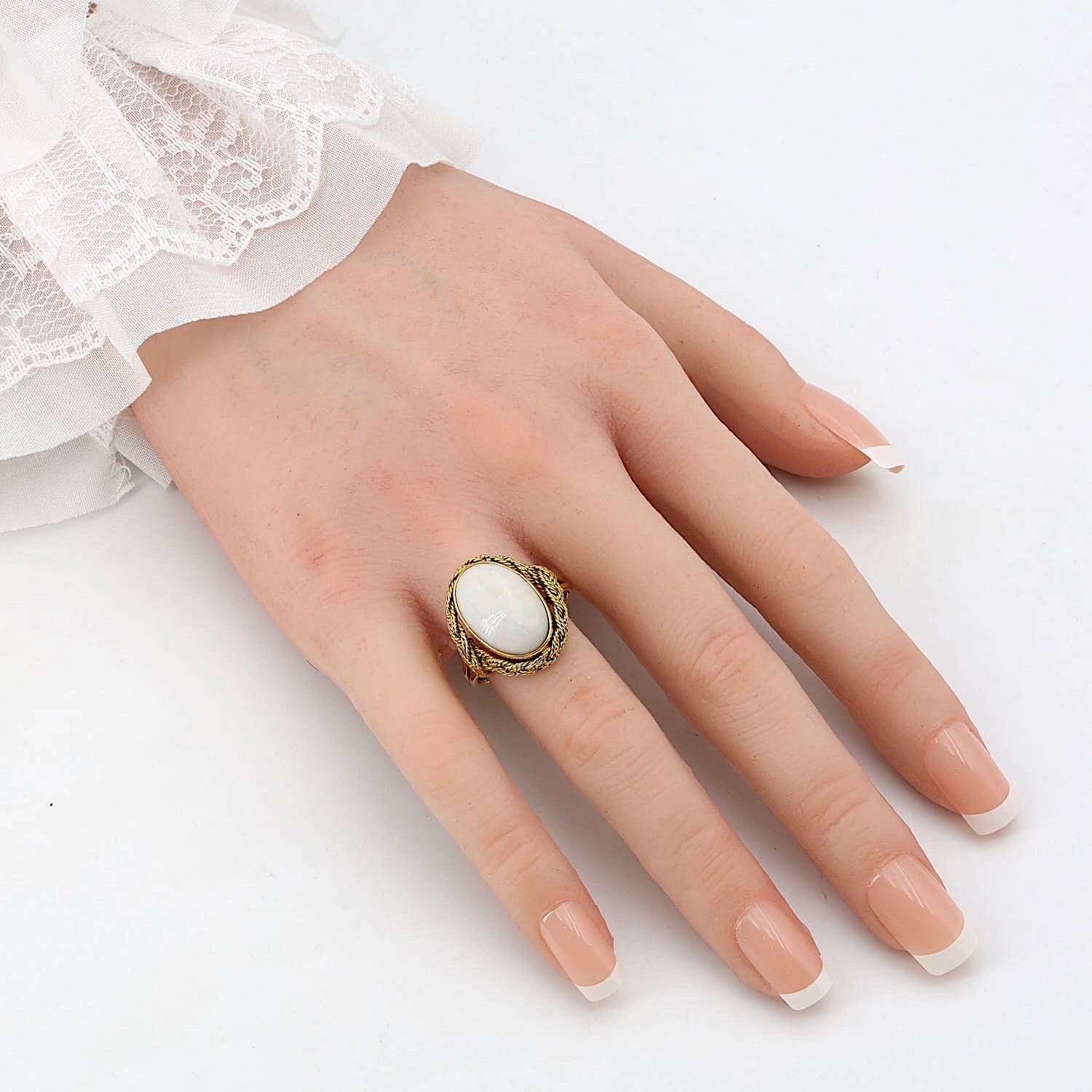 Ring in 750er Gelbgold mit einem weißen Opal, an der künstlichen Hand