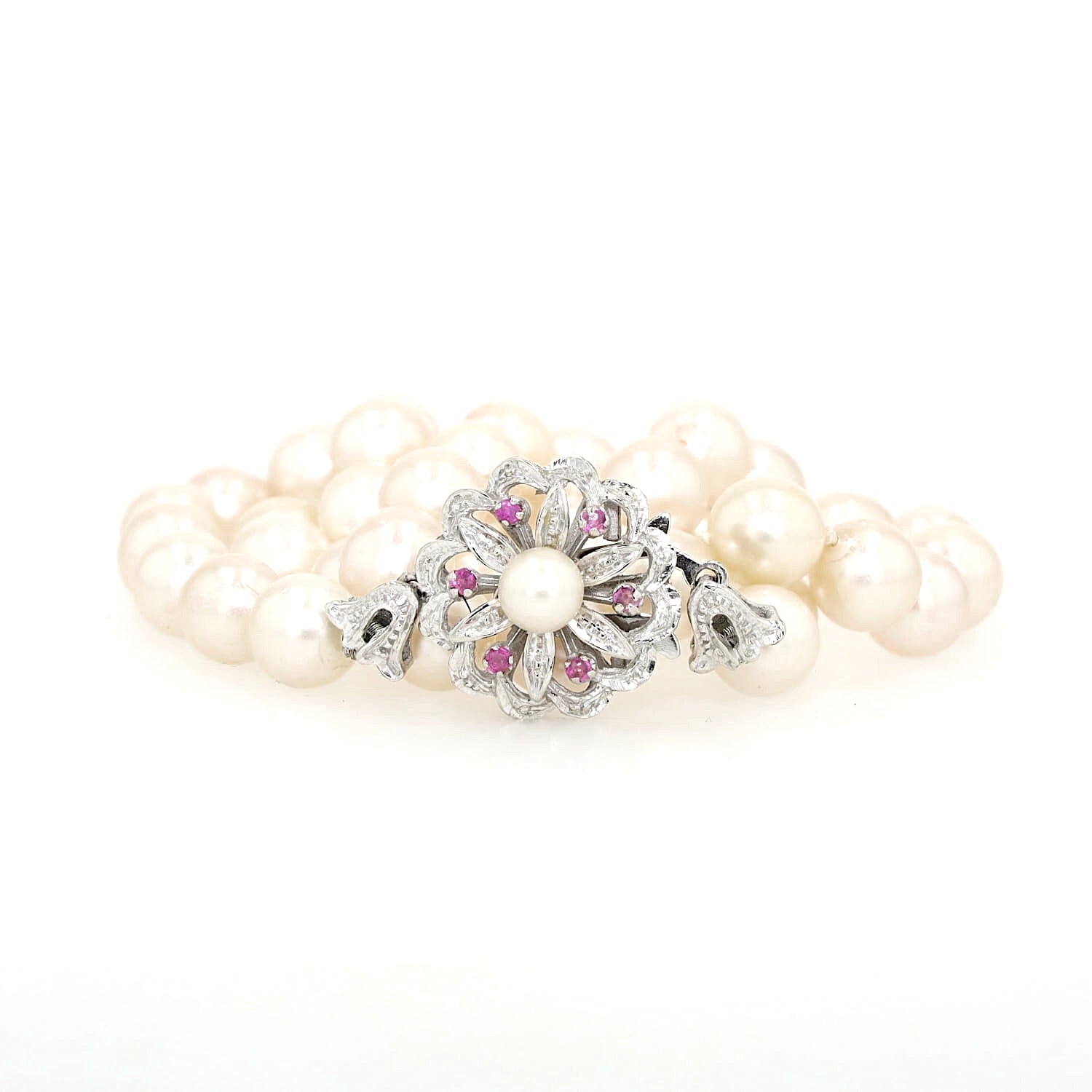 Akoya-Zuchtperlenkette mit einem 750er Weißgoldschloß mit Zuchtperle und Rubinen, zusammengerollt mit Schloss vorne