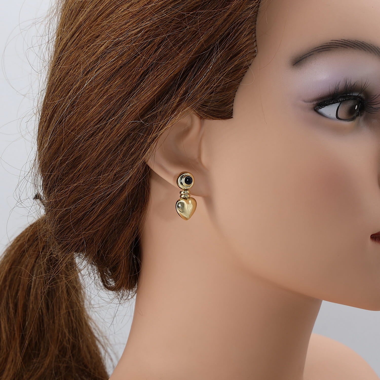 Paar Ohrringe in 750er Gelbgold mit je einem blauen Saphir-Cabochon, einzelnd mit Herz am Ohr einer Puppe