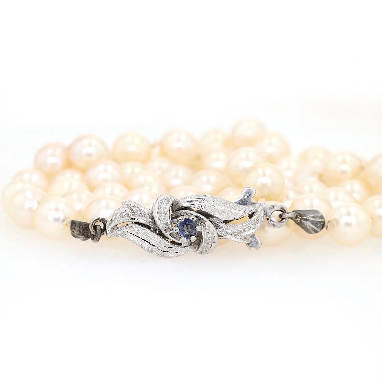 Akoya-Zuchtperlenkette mit einem Schloss aus 750er Weißgold mit einem blauen Saphir, aufgerollt mit Schloss vorne