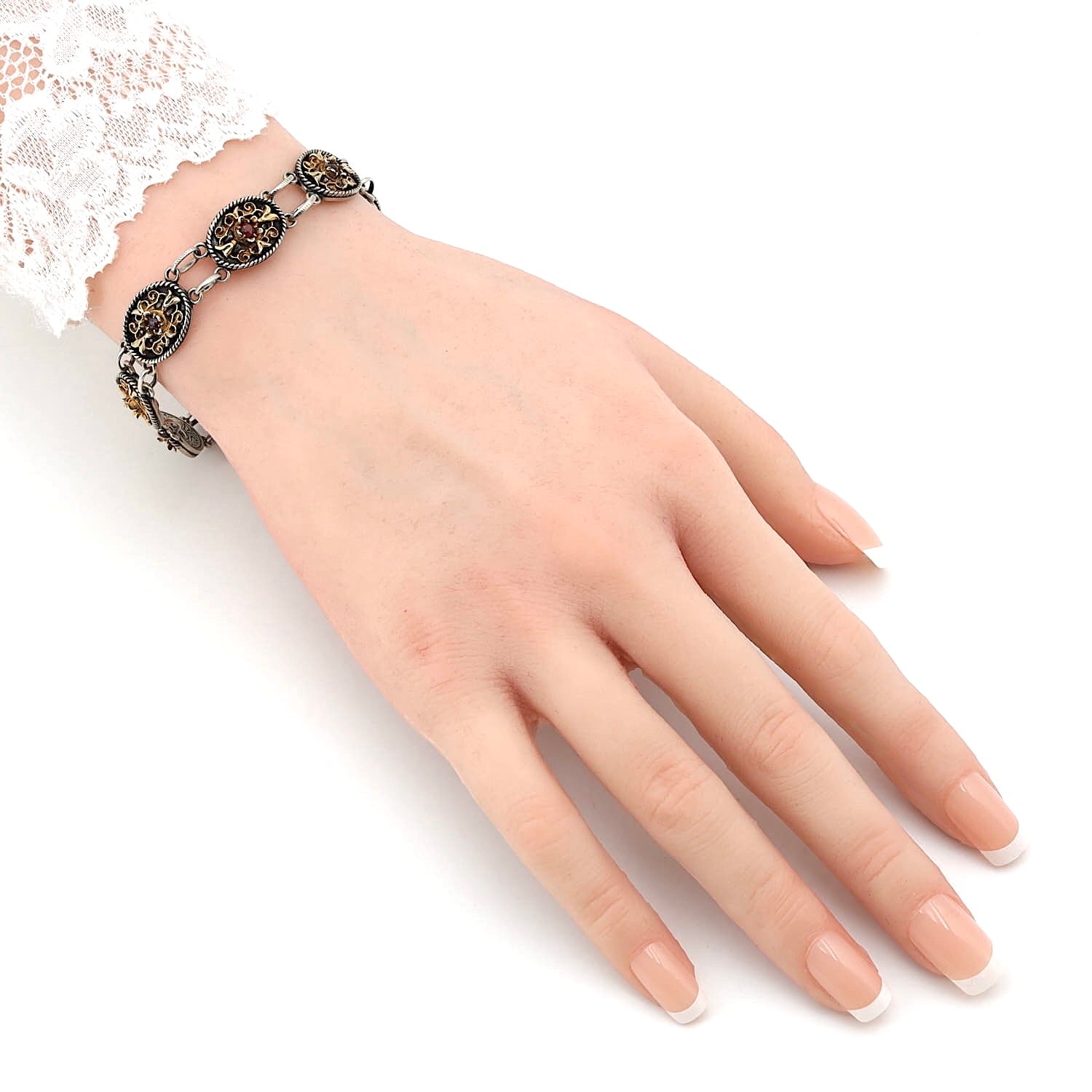 Trachtenarmband in 835er Silber mit Vergoldung und Granaten, an einem künstlichen Handgelenk