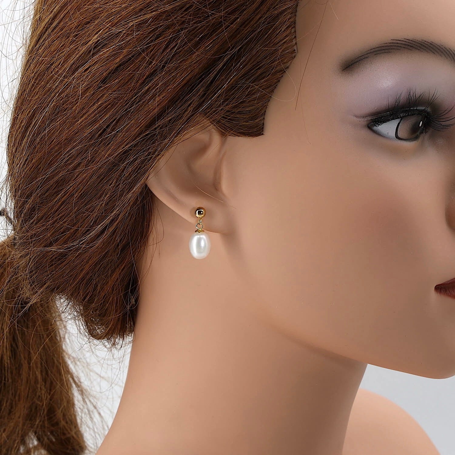Ohrringe in 750er Gelbgold mit je einer Zuchtperle, einzelnd hängend am Ohr einer Puppe