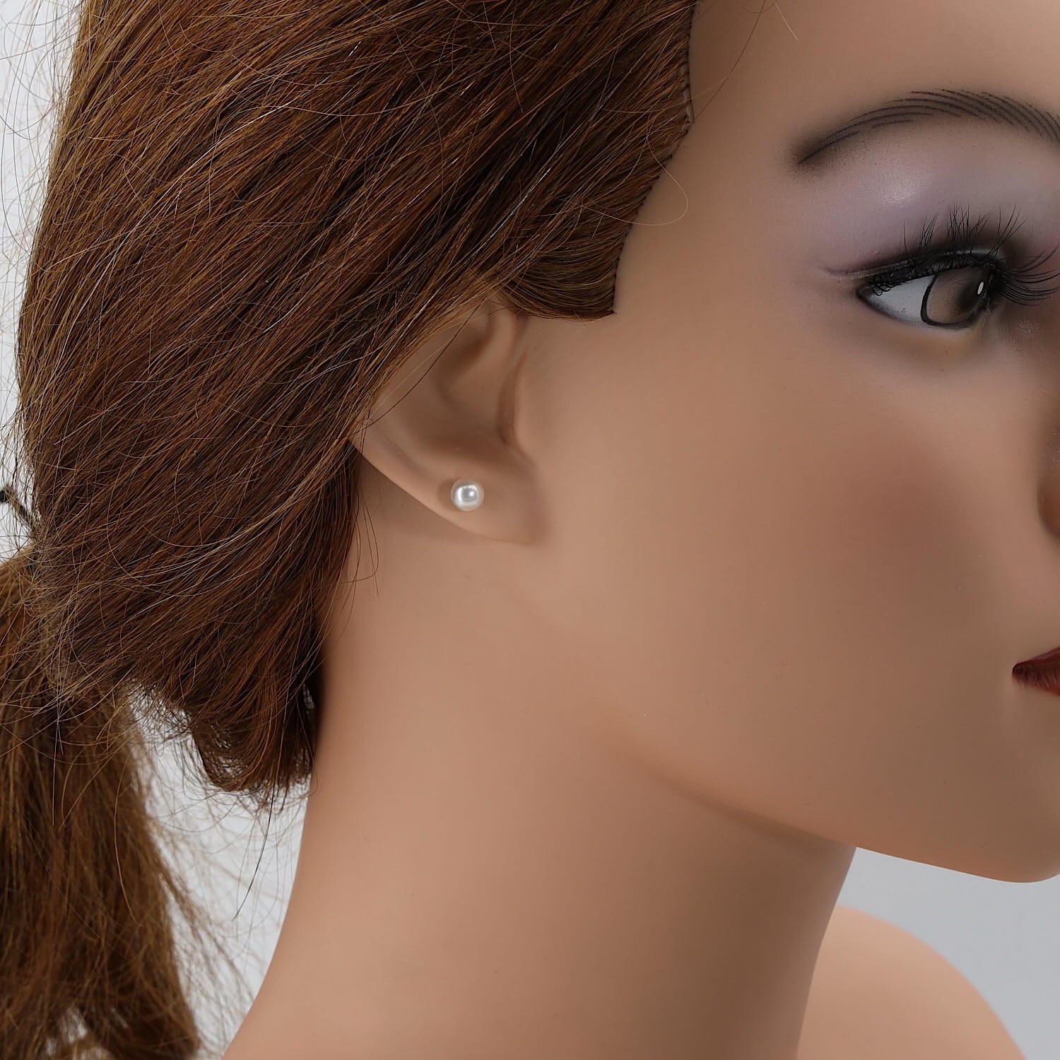 Ohrstecker in 750er Weißgold mit je einer Akoya-Zuchtperle, einzelnd am Ohr einer Puppe