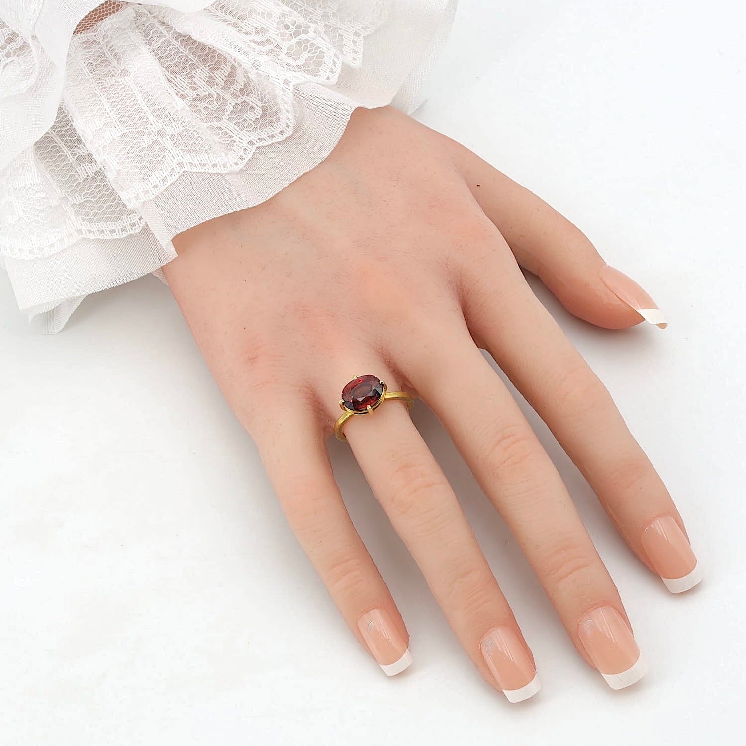 Ring aus der Werkstatt von „Der 4. König“ in 750er Gold mit einem natürlichen roten Zirkon, an einer künstlichen Hand