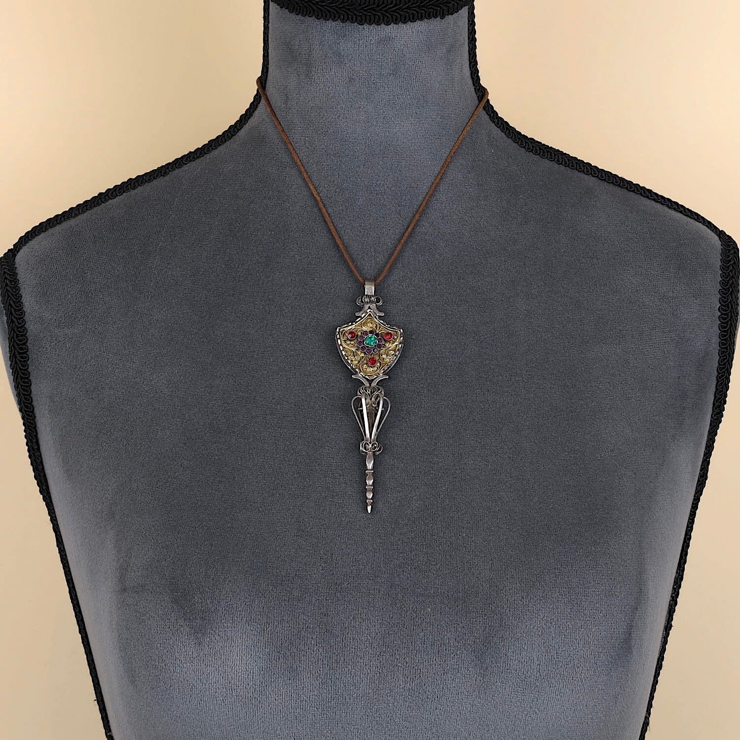 Antiker Miederstecker aus Silber mit Vergoldung und bunten Glassteinen, an einer dunklen Büste