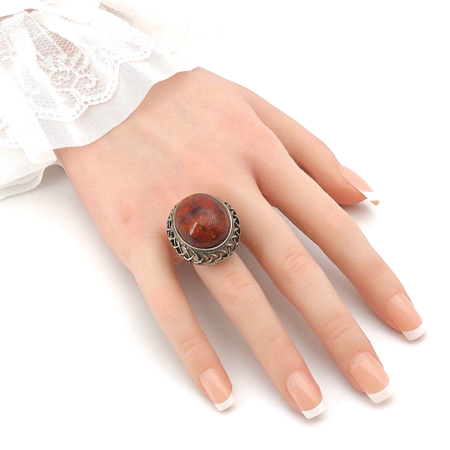 Statement ring silver plated with a large amber, on an artificial hand