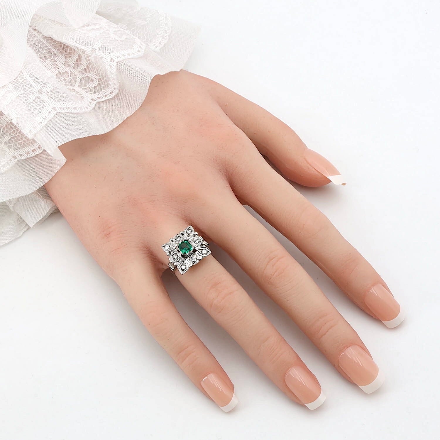 Art Deco Ring in 585er Weißgold mit einem Smaragd und Brillanten, an einer künstlichen Hand