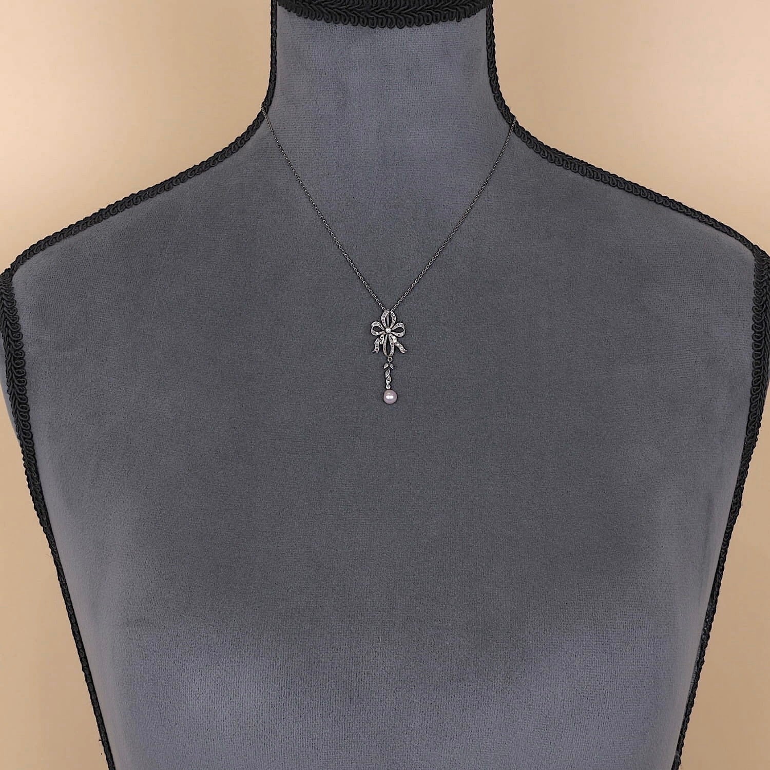 Belle Époque Kette mit einem Anhänger aus Platin mit Diamanten und einer Zuchtperle, an einer dunklen Büste