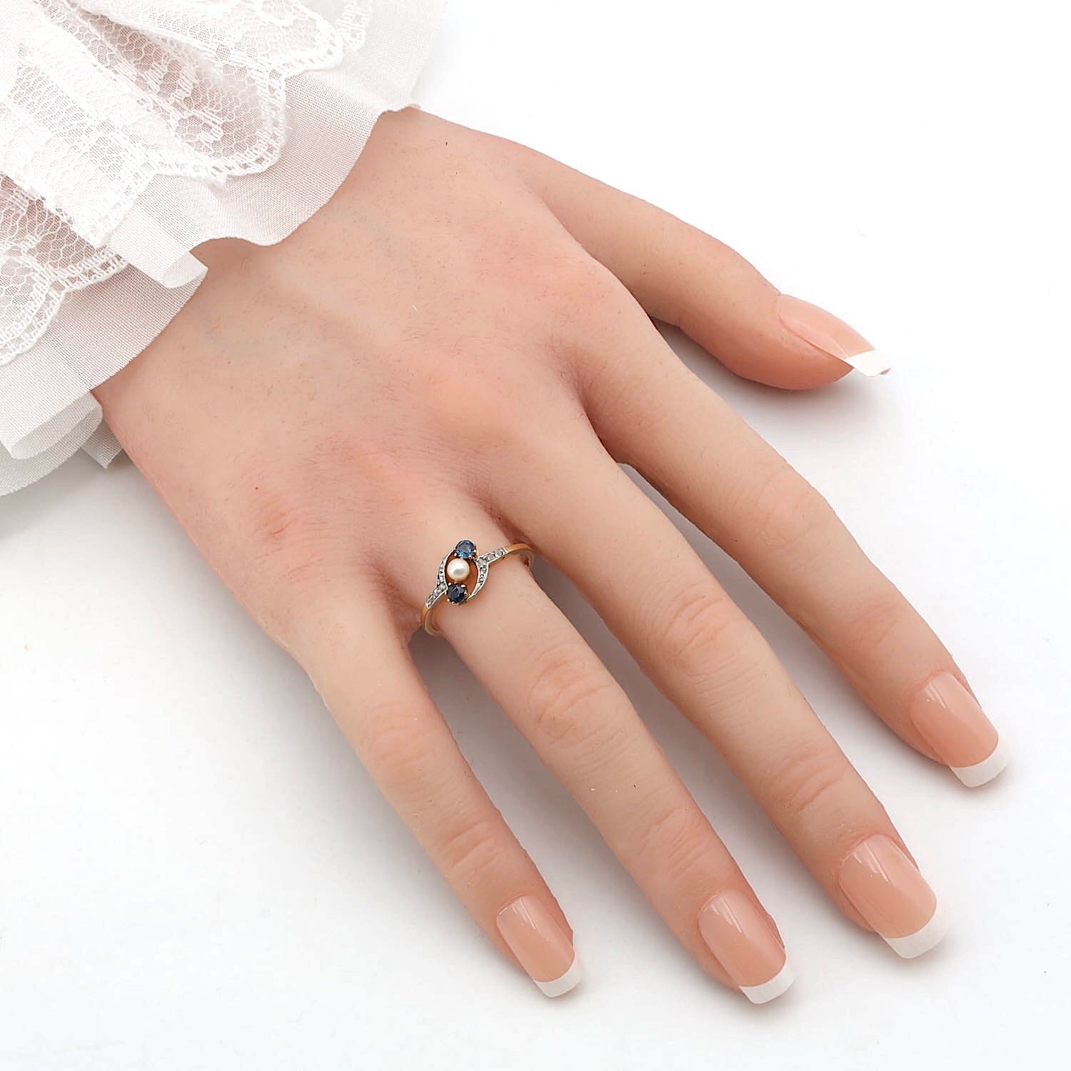 Jugendstil Ring in 585er Gelbgold, platiniert mit zwei blauen Saphiren, einer Perle und Diamanten, an einer künstlichen Hand