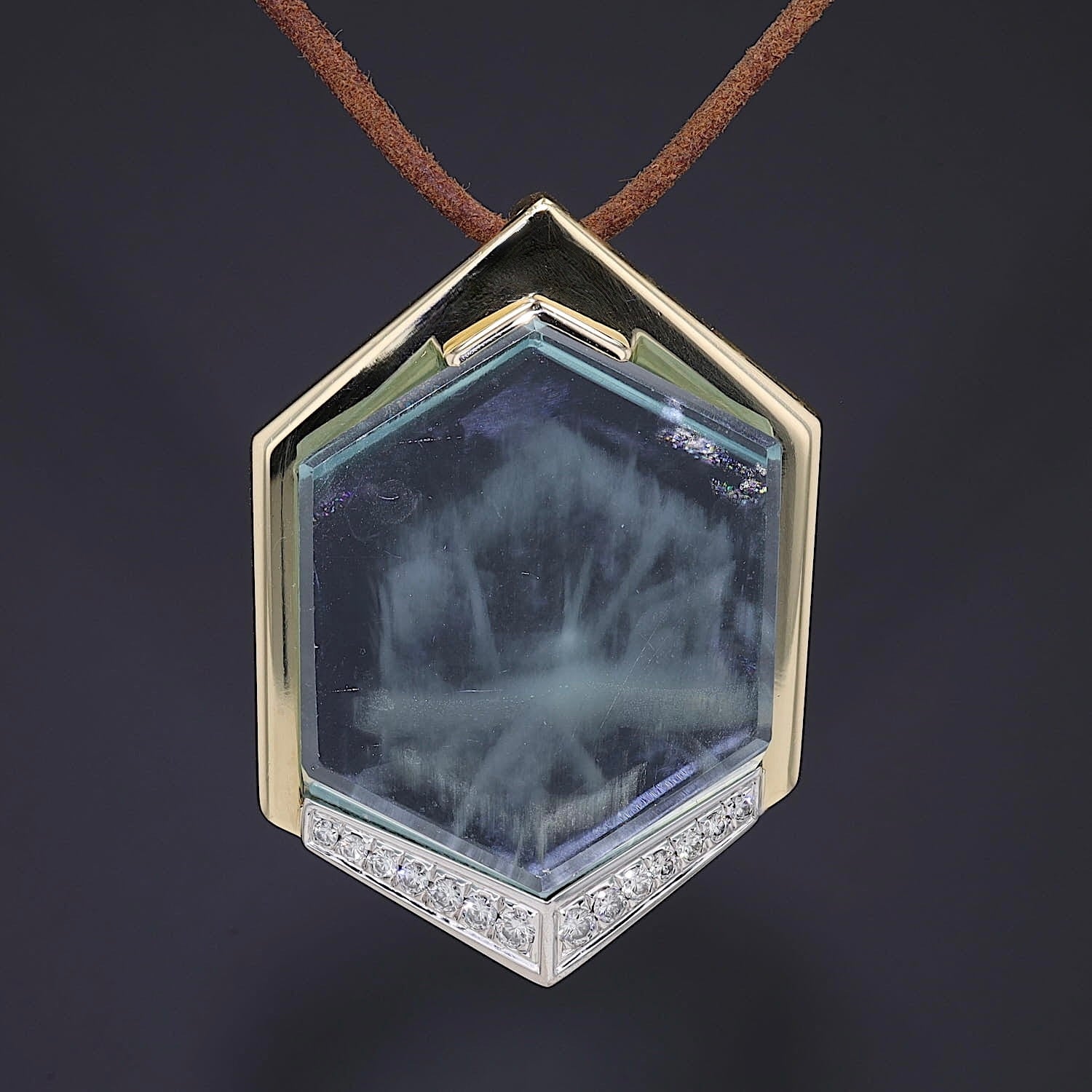 Pendant in 750 yellow gold with a large aquamarine weighing approx. 54 ct, hanging frontally on a dark background