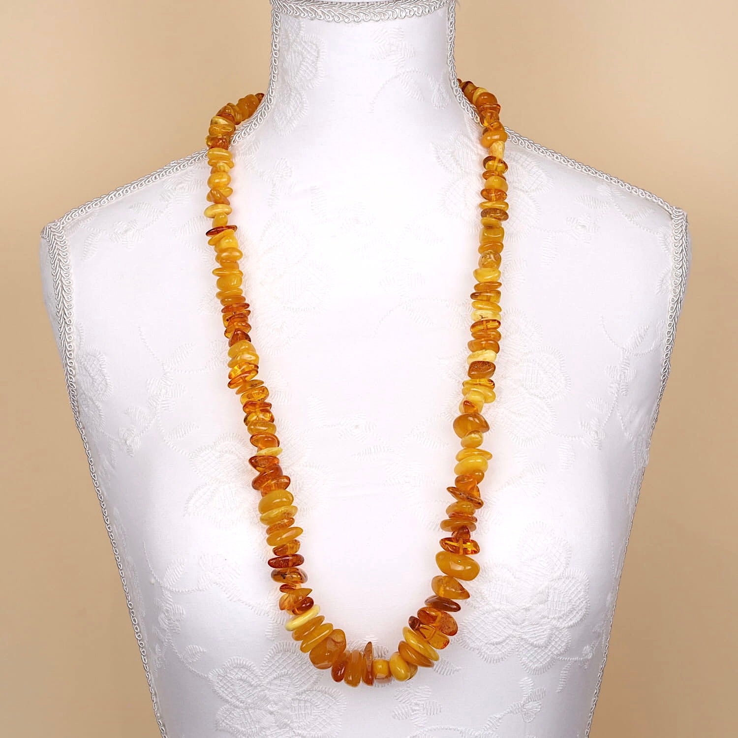 Large long vintage amber necklace, partly butterscotch, on a white bust