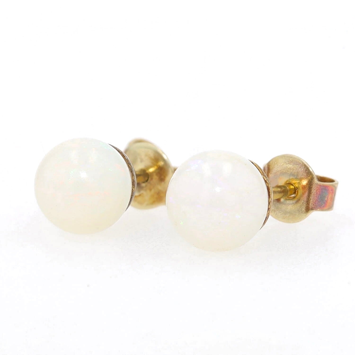 Pair of stud earrings in 585 yellow gold, each with a white opal ball, turned left