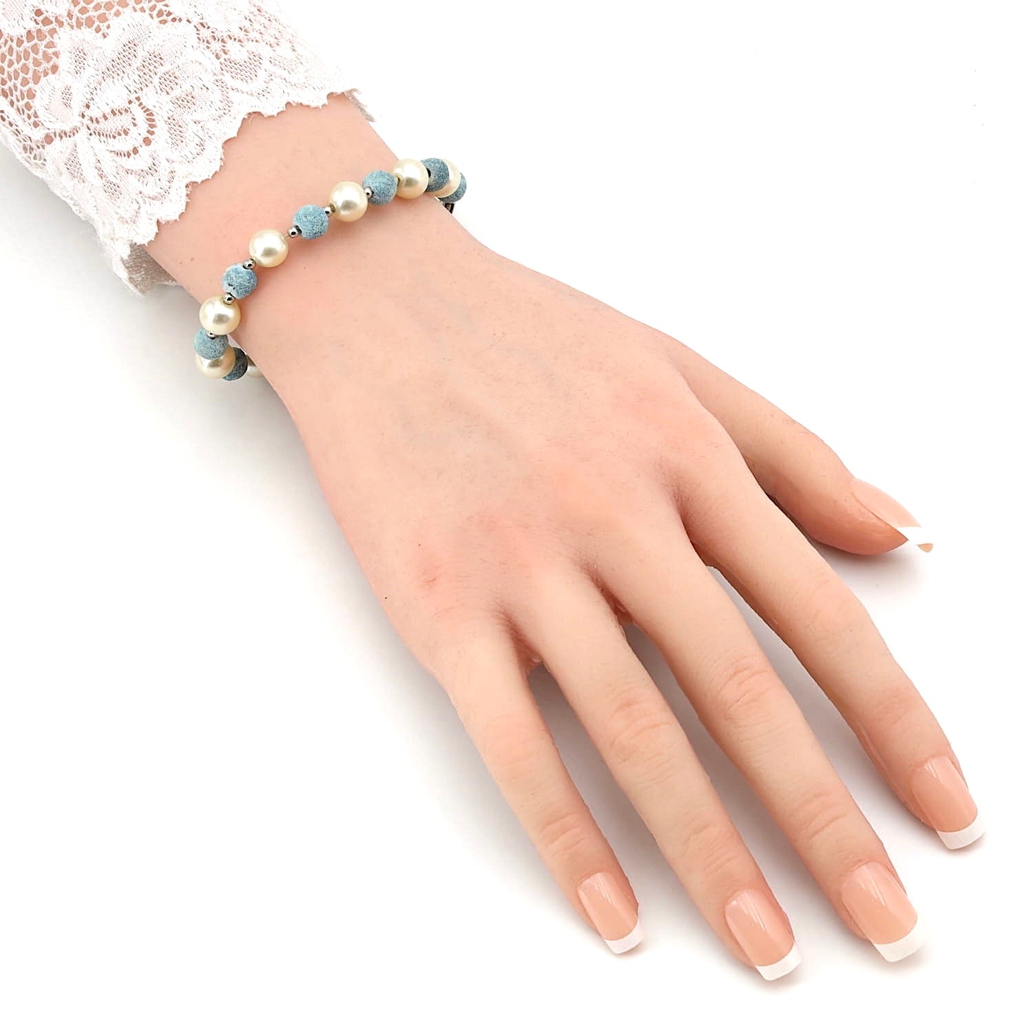 Armband aus Metalldraht mit Perlenimitationen, Wurzelkorallen und kleinen Metallkugeln, an einem künstlichen Arm