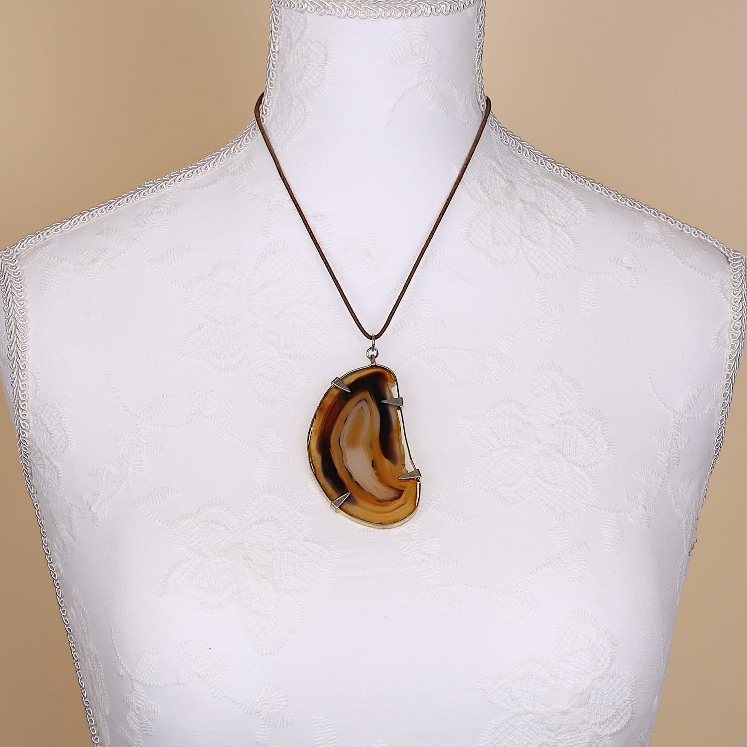Large pendant made of agate set in metal, on a large white bust