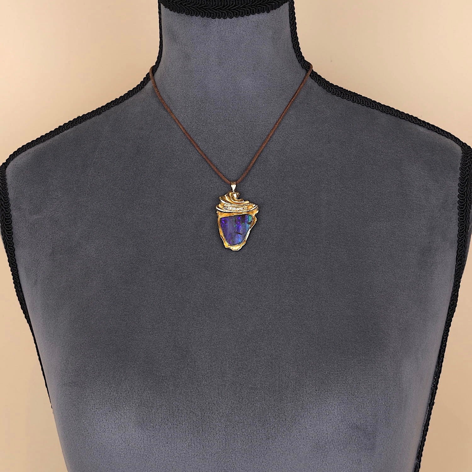 Anhänger in 585er Gelbgold mit einem schwarzen Edelopal und Brillanten, an einer dunklen Büste