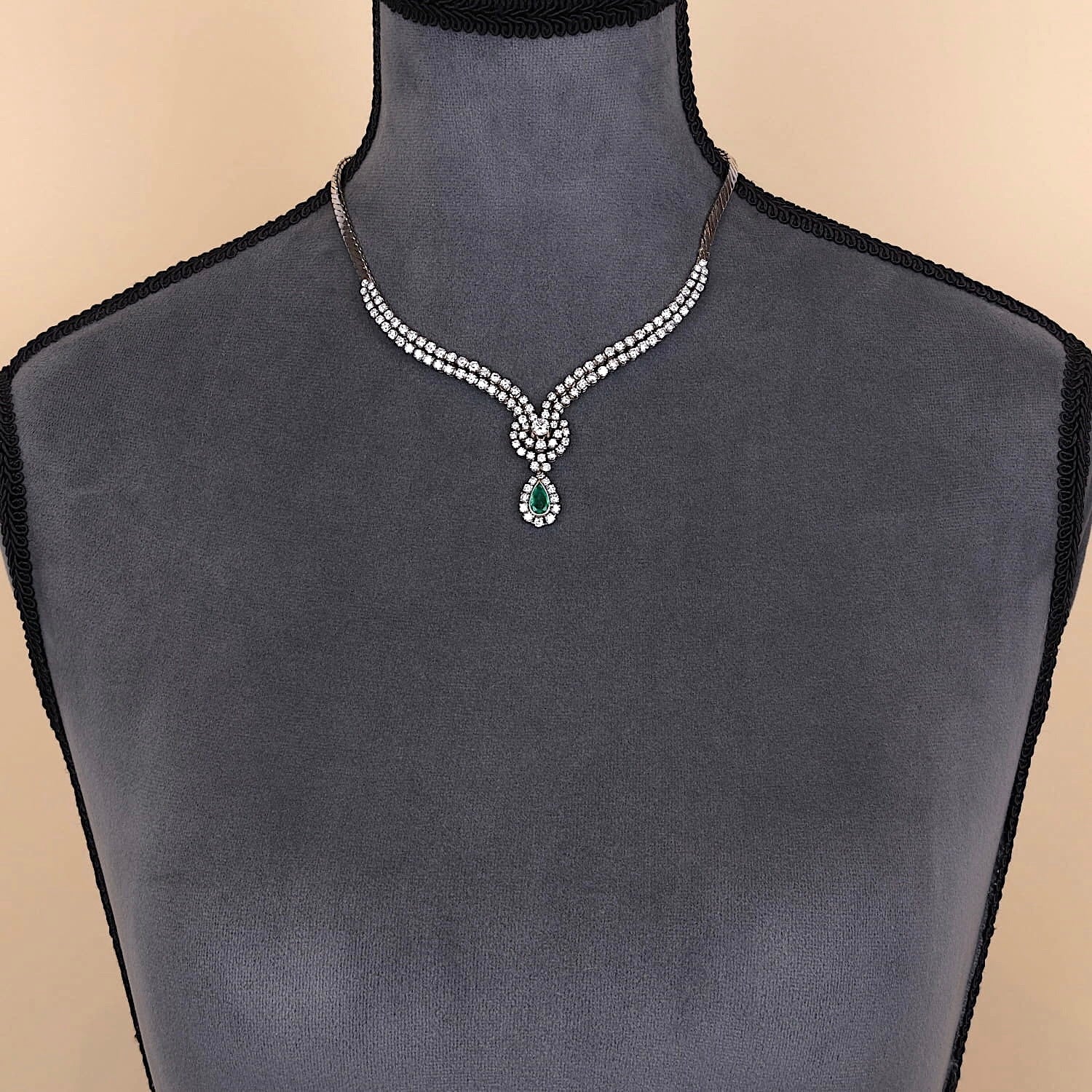 Juwelen-Collier in 750er Weißgold mit ca. 7,0 ct Brillanten und einem Smaragd, an einer dunklen Büste