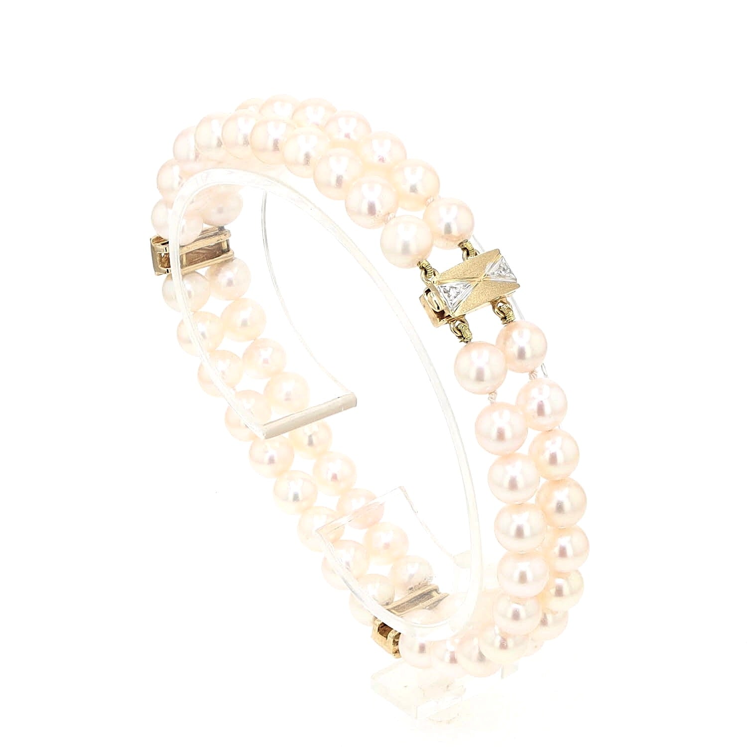 Akoya-Zuchtperlenarmband in zwei Reihen mit einem Schloss und Goldelementen aus 585er Gelbgold mit Diamanten, stehend auf einem Halter aus Kunststoff leicht rechts gedreht