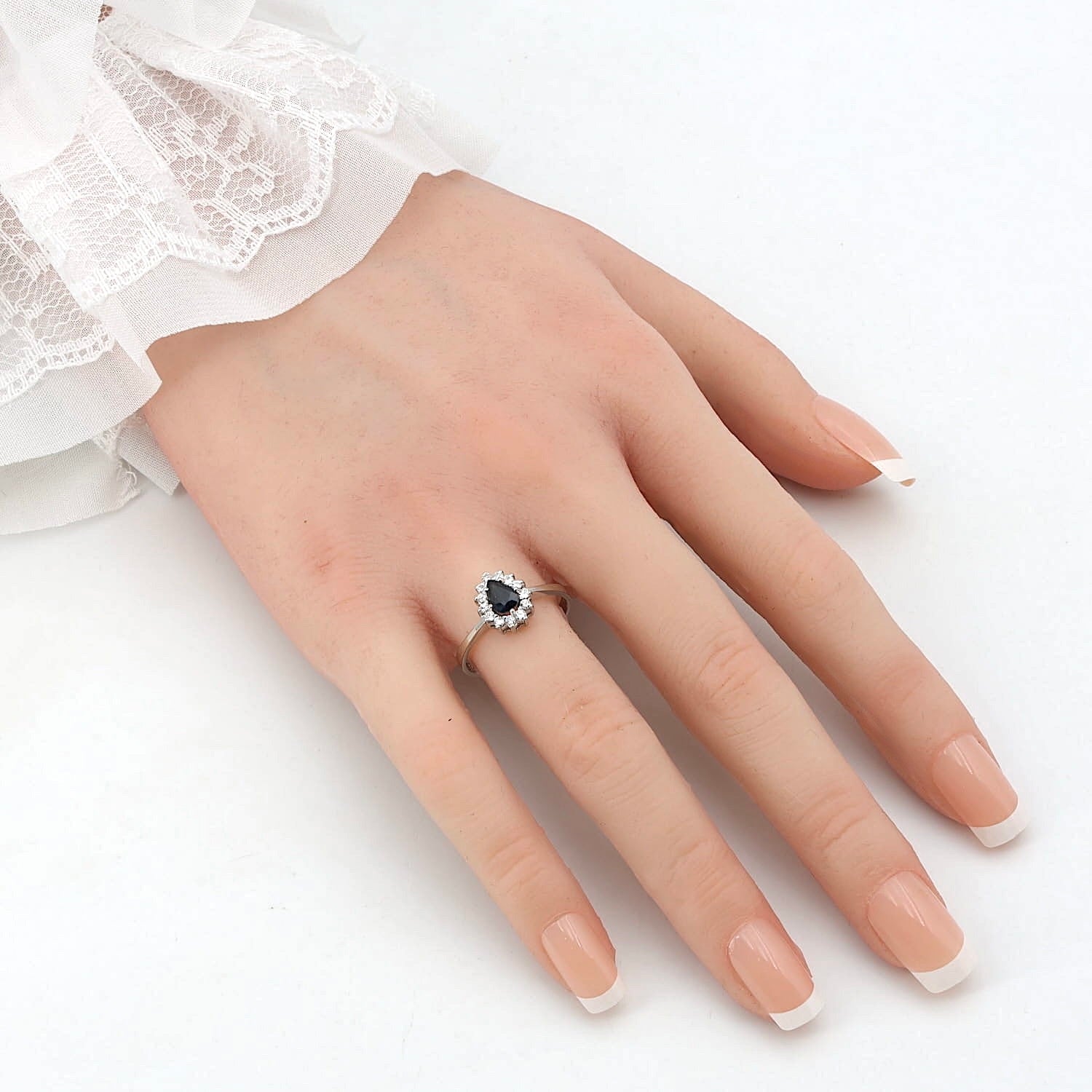 Ring in 585er Weißgold mit einem blauen Saphir und Brillanten, an einer künstlichen Hand