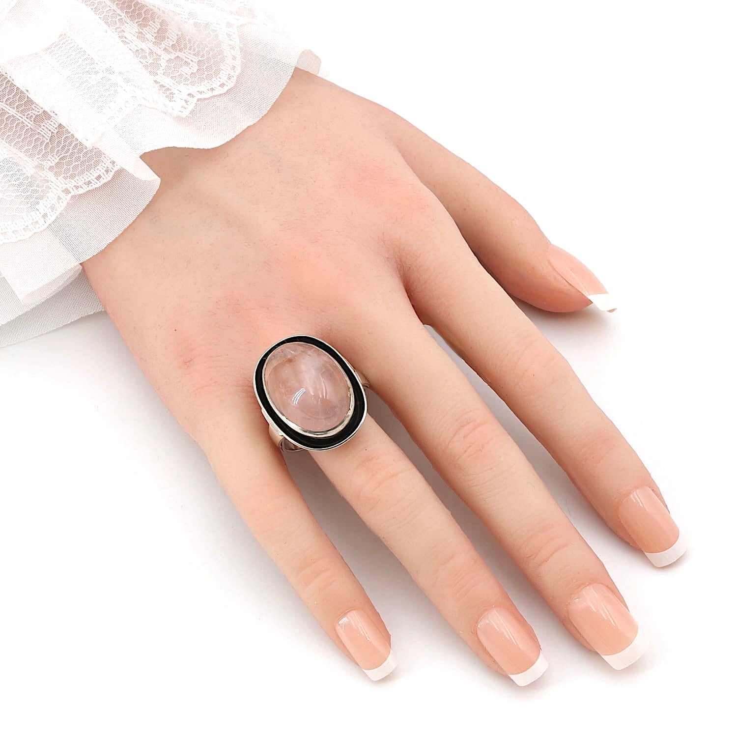 Vintage-Ring in Silber mit einem Rosenquarz-Cabochon, an einer künstlichen Hand