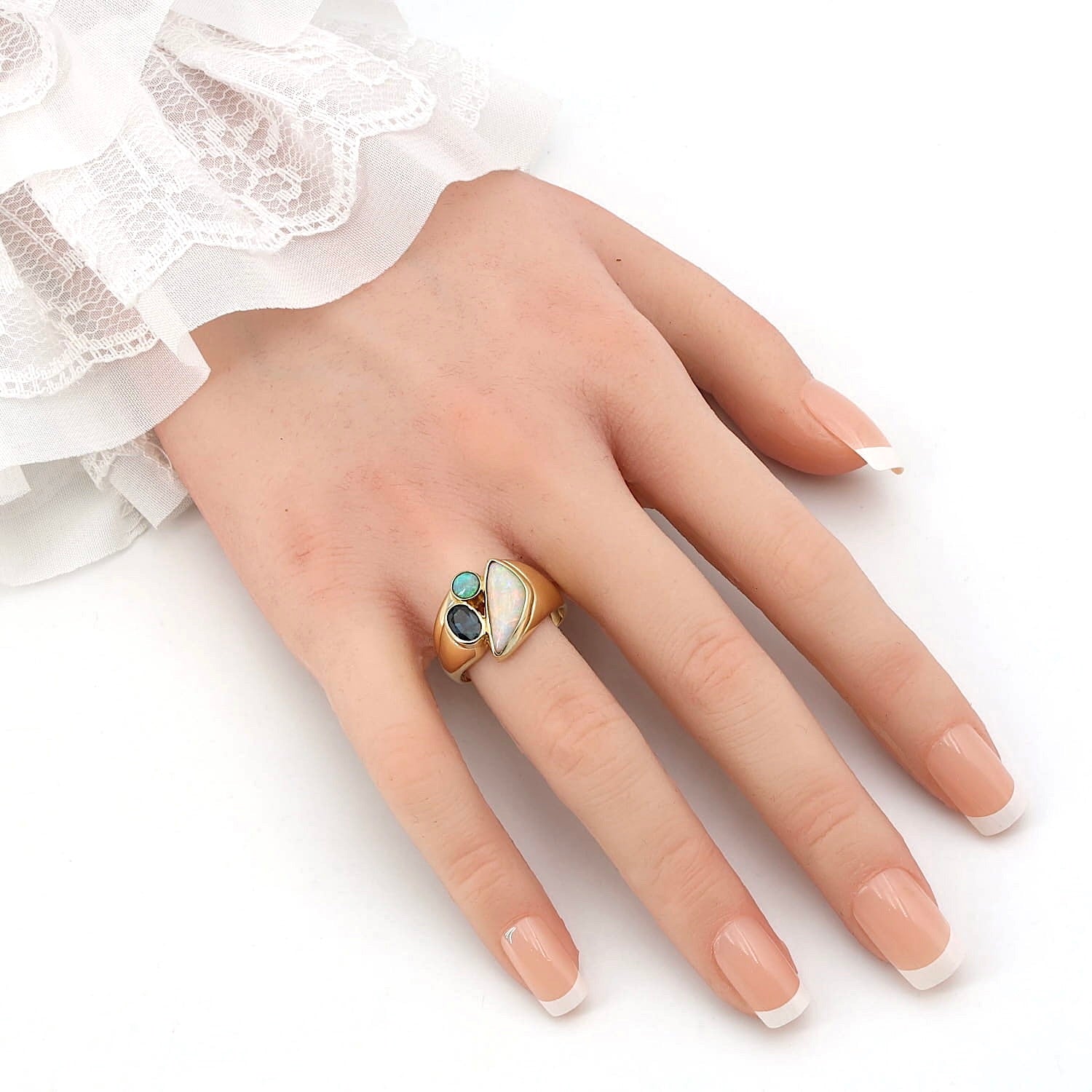 Ring in 750er Gelbgold mit einem blauen Saphir und Opalen, an einer künstlichen Hand