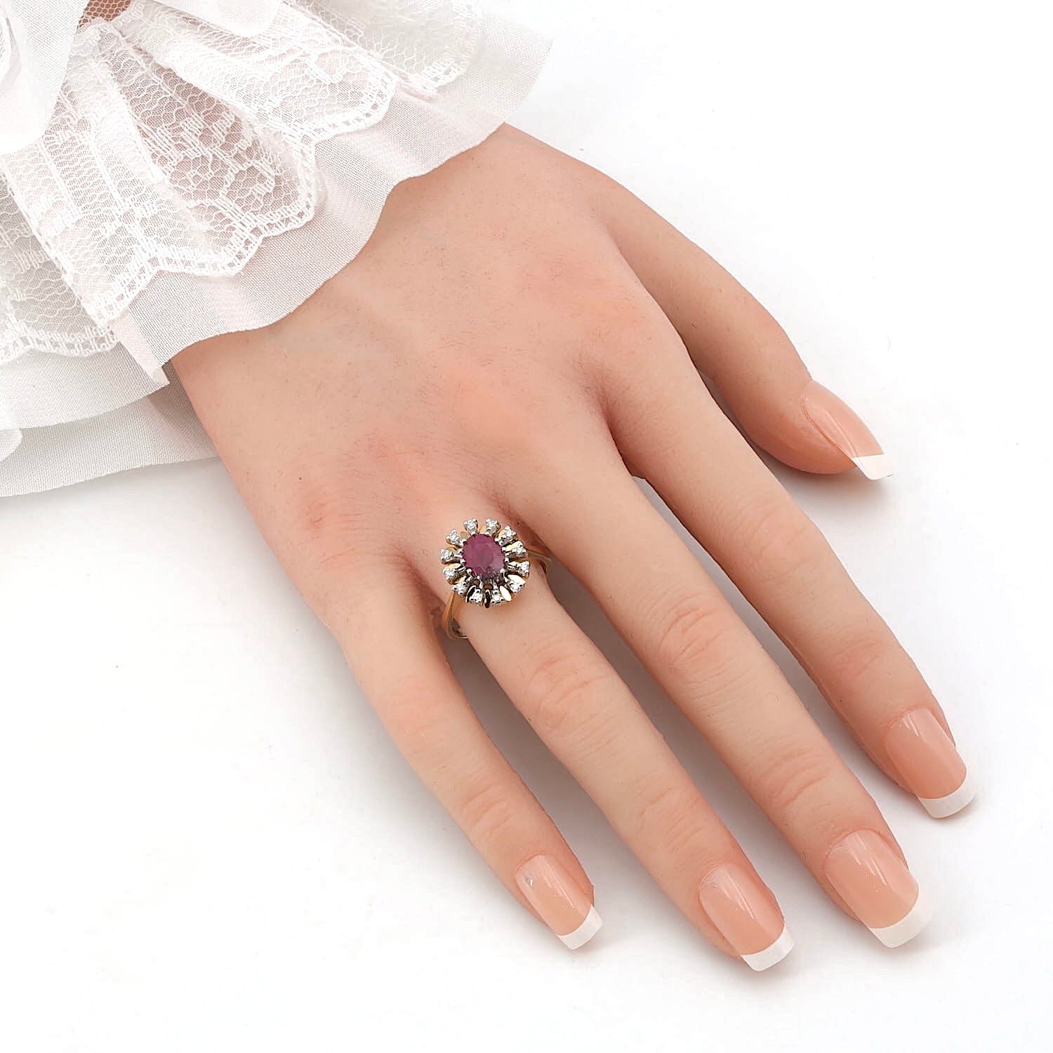 Ring in 585er Gelb- und Weißgold mit einem Rubin und Diamanten, an einer künstlichen Hand
