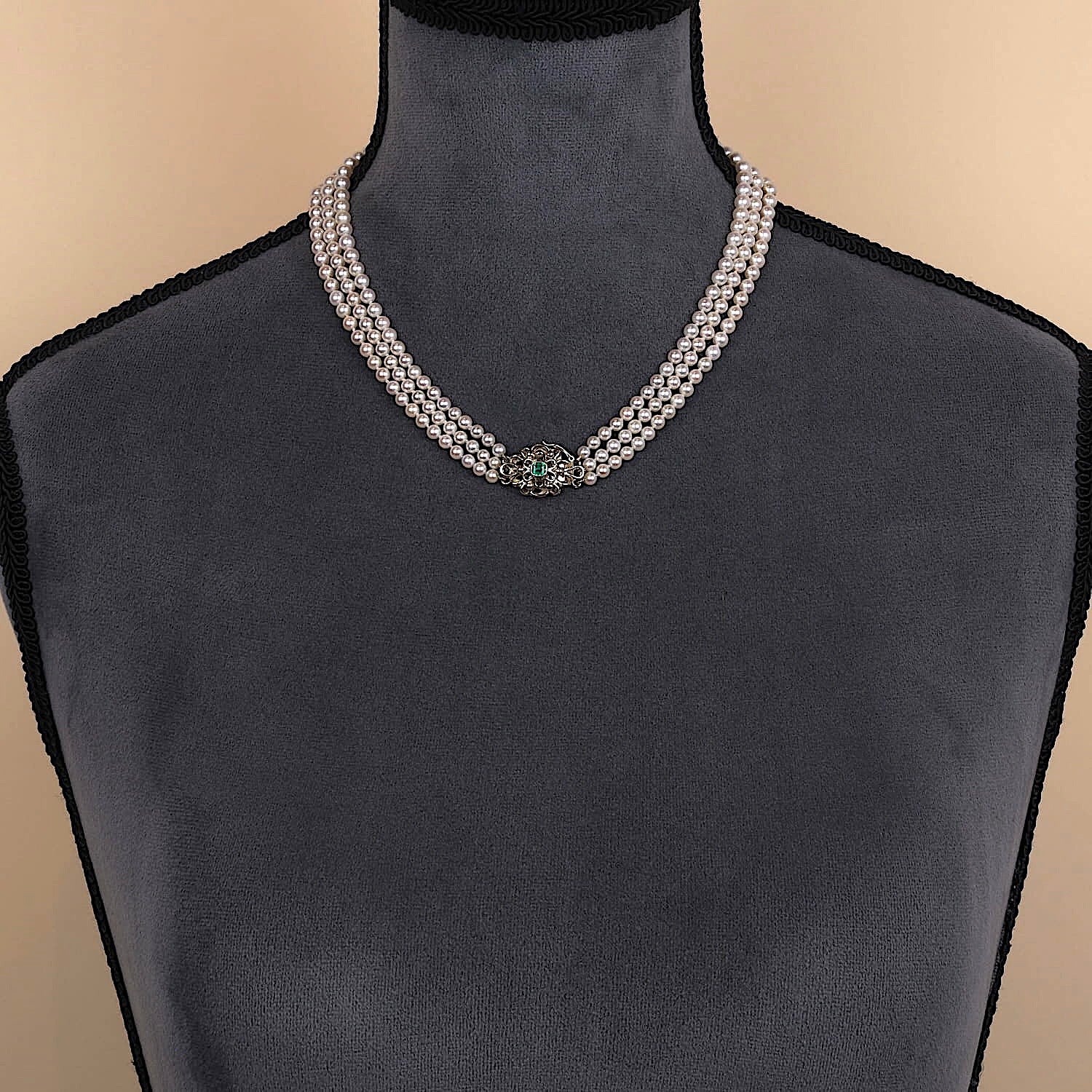 Wien - Art Deco Zuchtperlencollier mit drei Strängen im Verlauf, Schloss 585er Gelbgold mit einem Smaragd, an einer dunklen Büste Schloss vorne