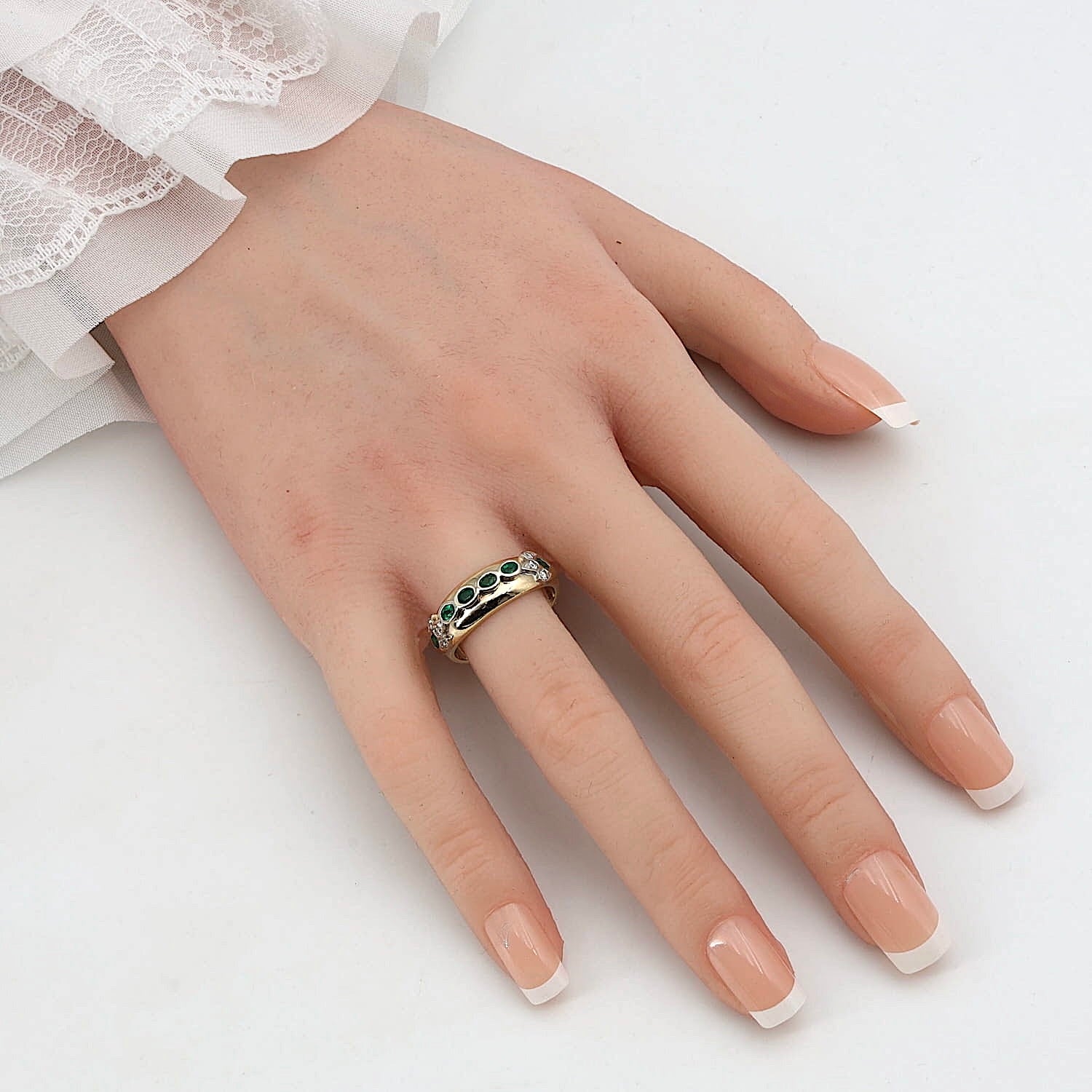 Ring in 585er Gelb- und Weißgold mit Smaragden und Brillanten, an einer künstlichen Hand 