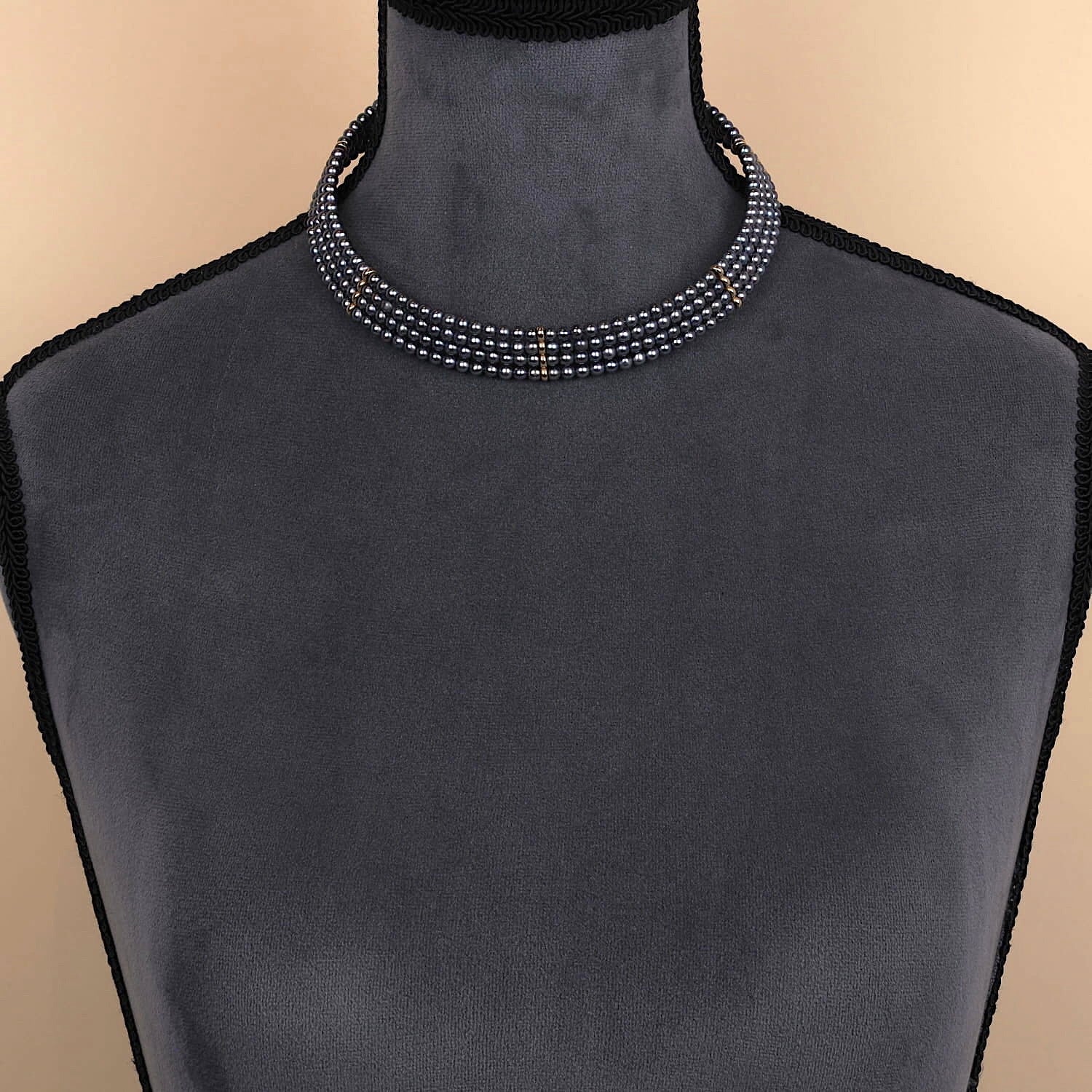 Halsreif aus 4 Reihen Peacock-Zuchtperlen und 585er Gelbgoldelementen, an einer dunklen Büste