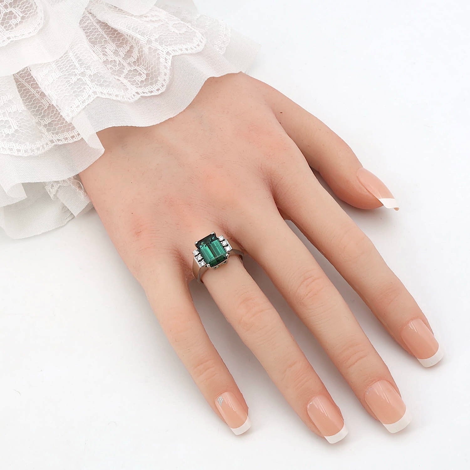 Cocktailring in 585er Weißgold mit einem grünen Turmalin und Brillanten, an einer künstlichen Hand