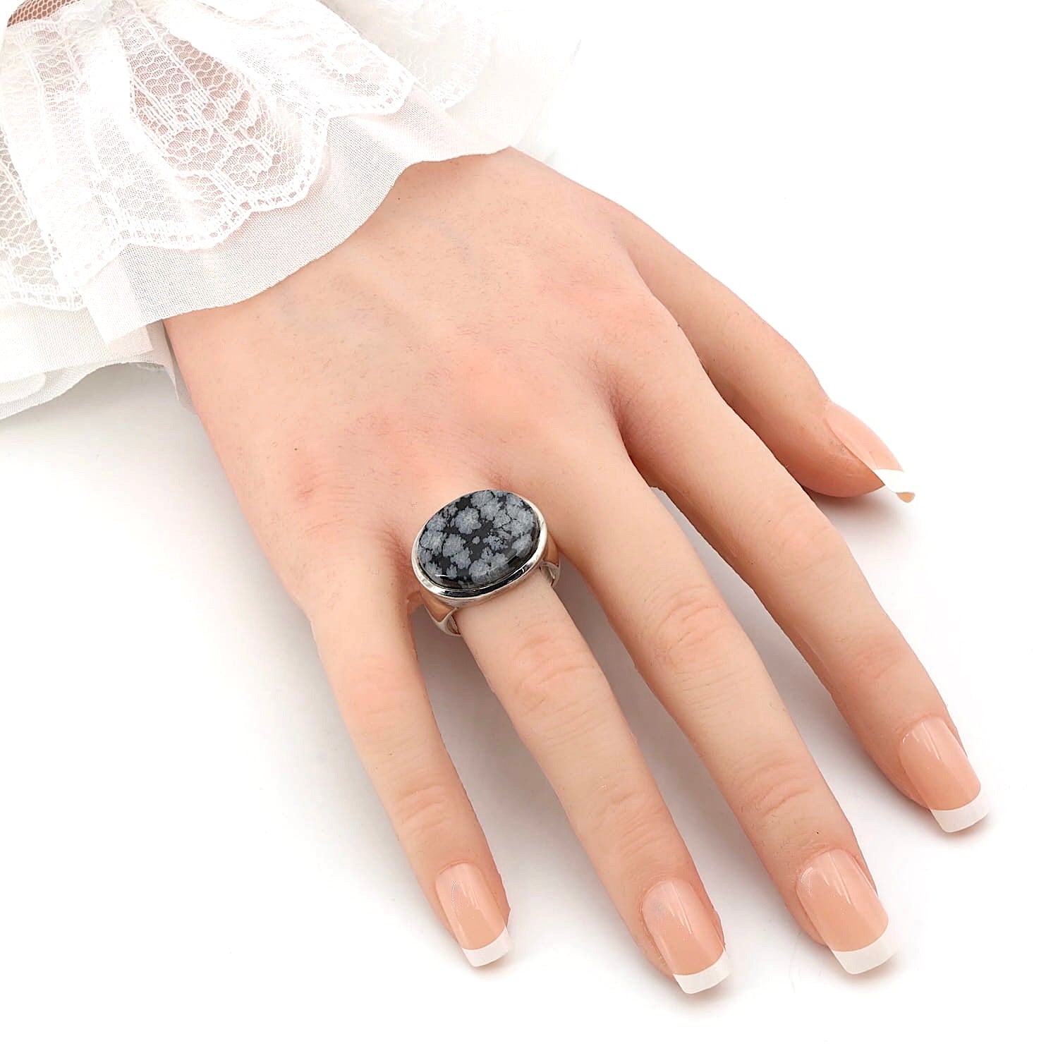 Ring in 925er Silber mit einem Schneeflockenobsidian, an einer künstlichen Hand