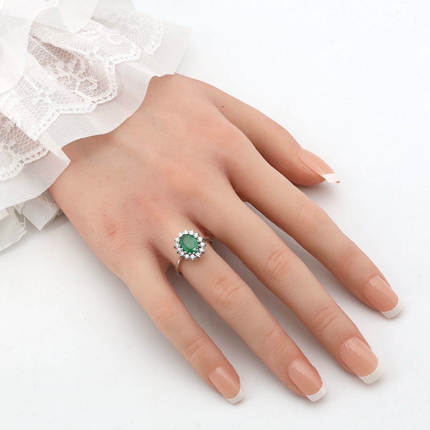 Ring in 585er Weißgold mit einem Smaragd und Brillanten, an einer künstlichen Hand