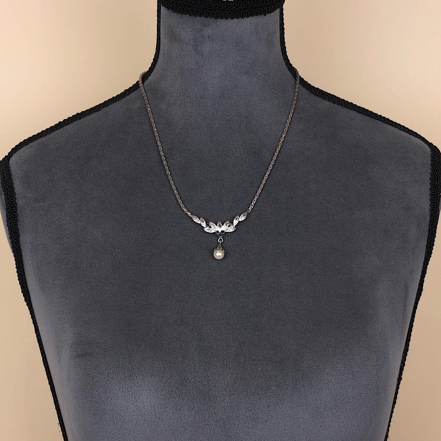 Kette in 835er Silber mit einer Zuchtperle und blauen Saphiren, an einer dunklen Büste