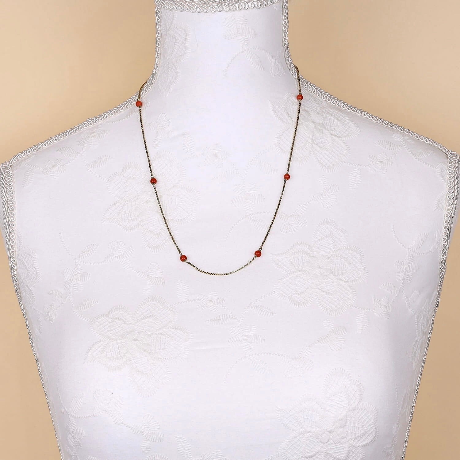 Kette in 333er Gold mit kleinen Korallenkugel, an einer weißen Büste