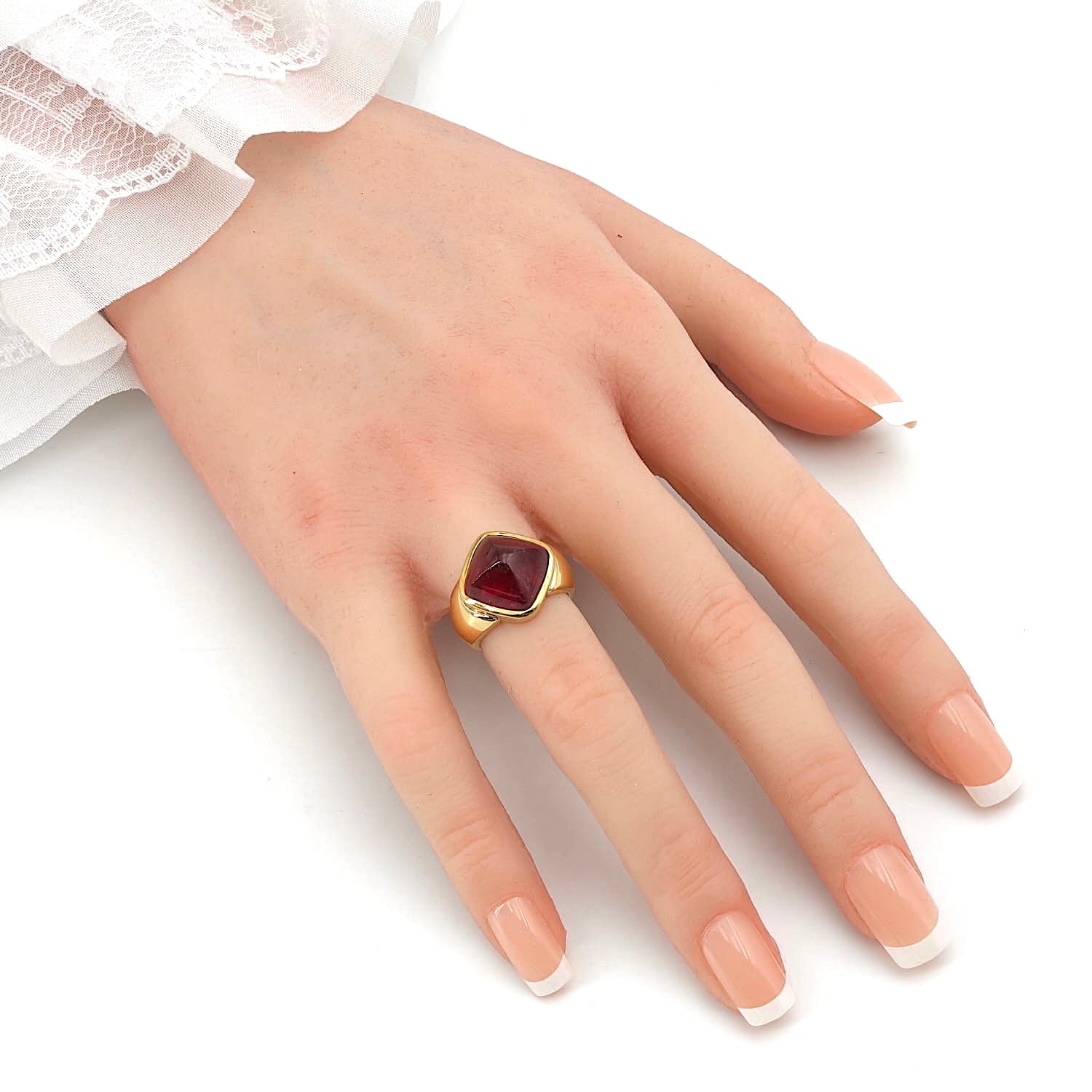Ring in 750er Gelbgold mit einem Rubellit-Cabochon, an einer künstlichen Hand