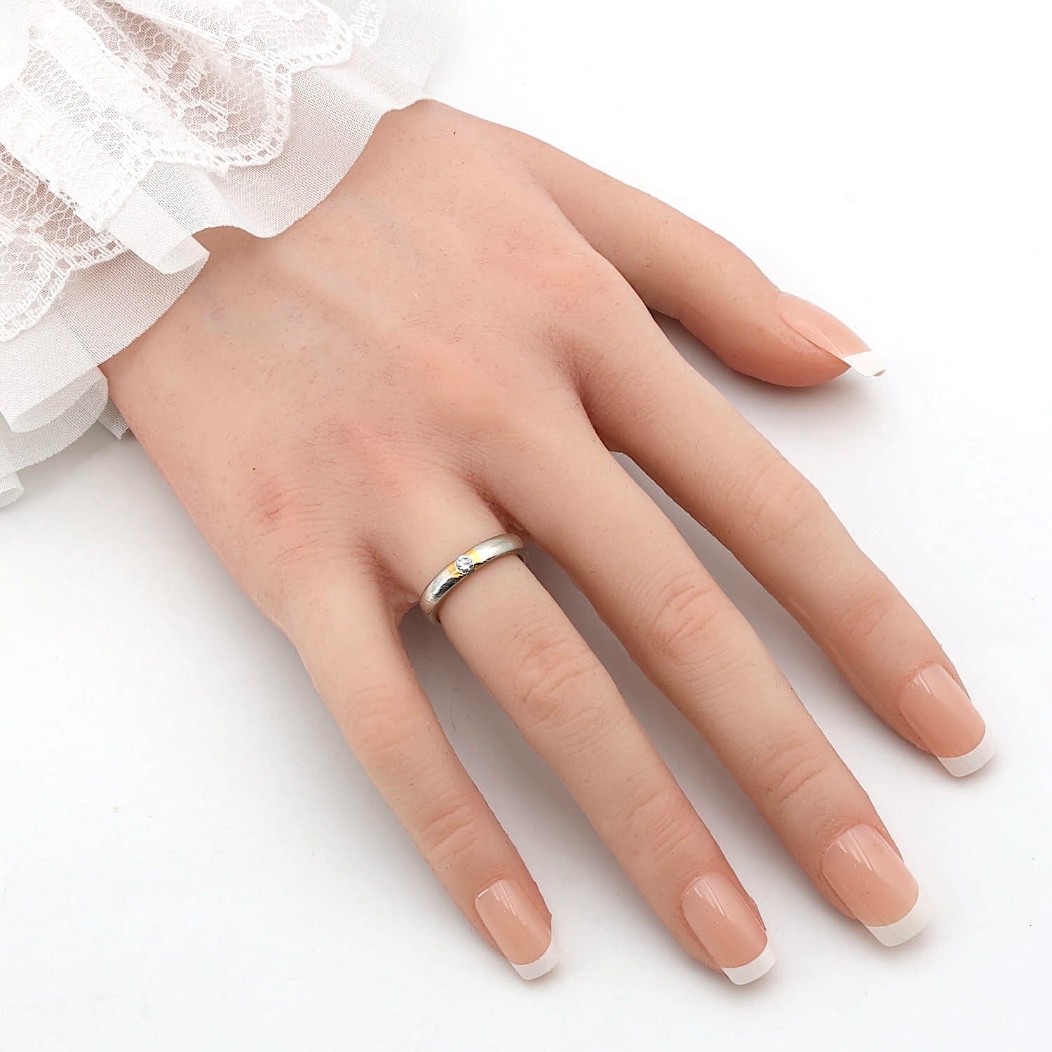 Henrich & Denzel Ring in 950er Platin mit Goldauflage und einem Brillanten ca. 0,10 ct, an einer künstlichen Hand