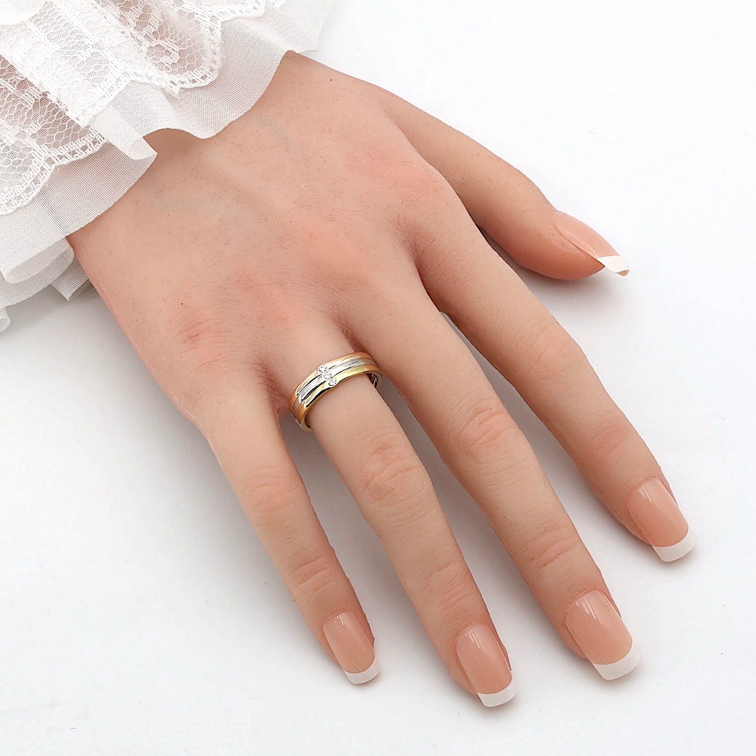 Niessing Ring Tricolor in zweifarbigen 750er Gold und Platin mit 3 Brillanten, an einer künstlichen Hand