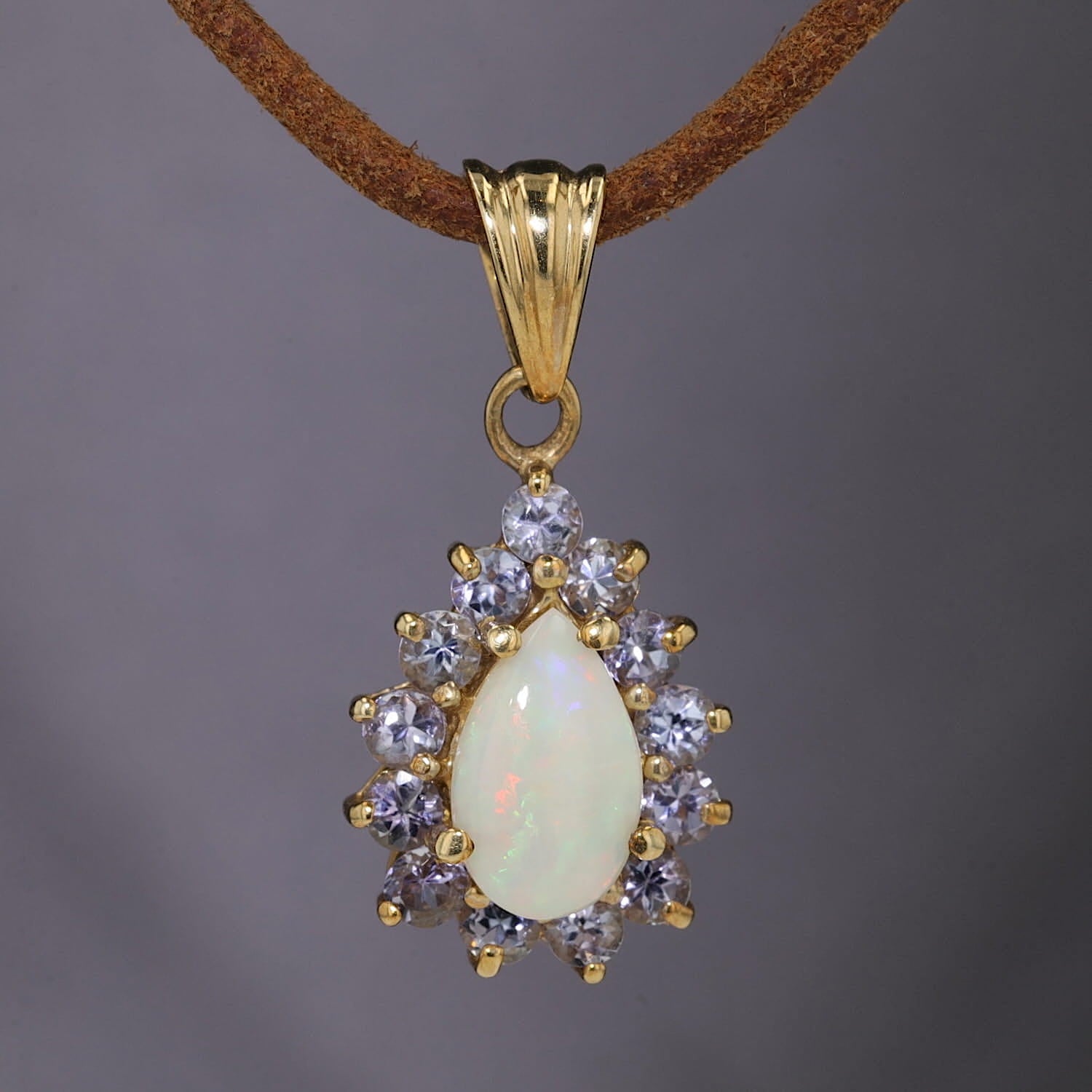 Anhänger in 375er Gelbgold mit einem Opal und Tansaniten, hängend frontal auf dunklen Hintergrund