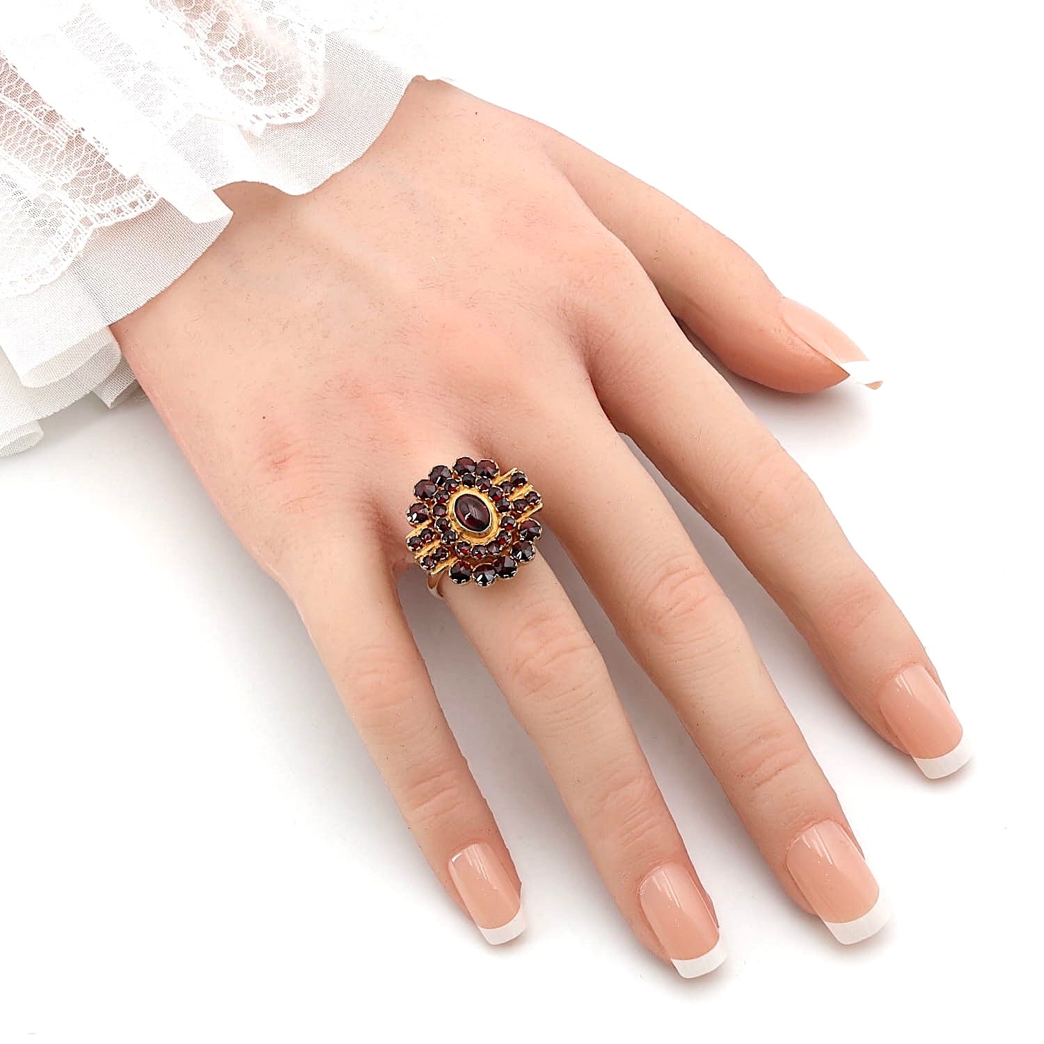Ring in 900 silver, gold-plated with garnets, on an artificial hand