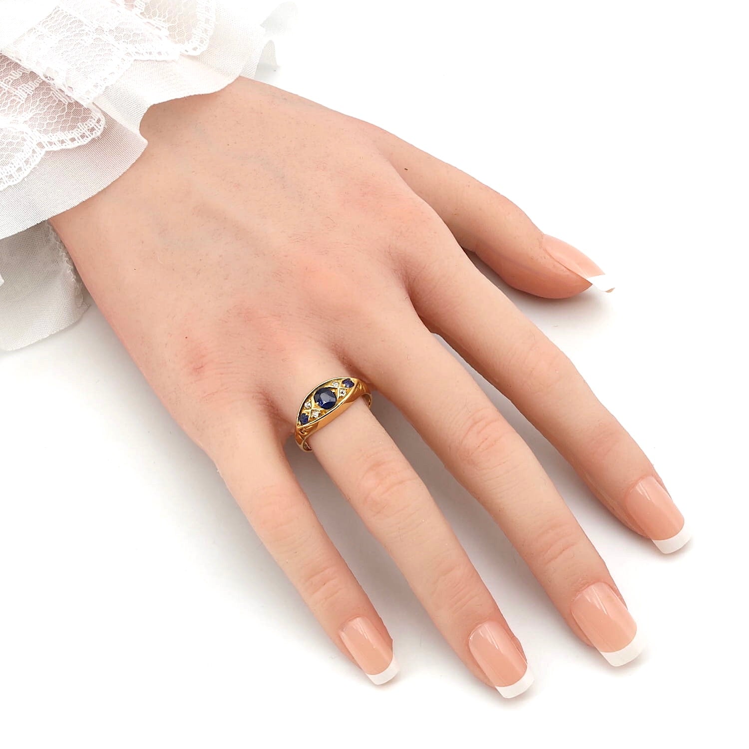 Edwardian ring in 750 yellow gold with blue sapphires and diamonds, on an artificial hand