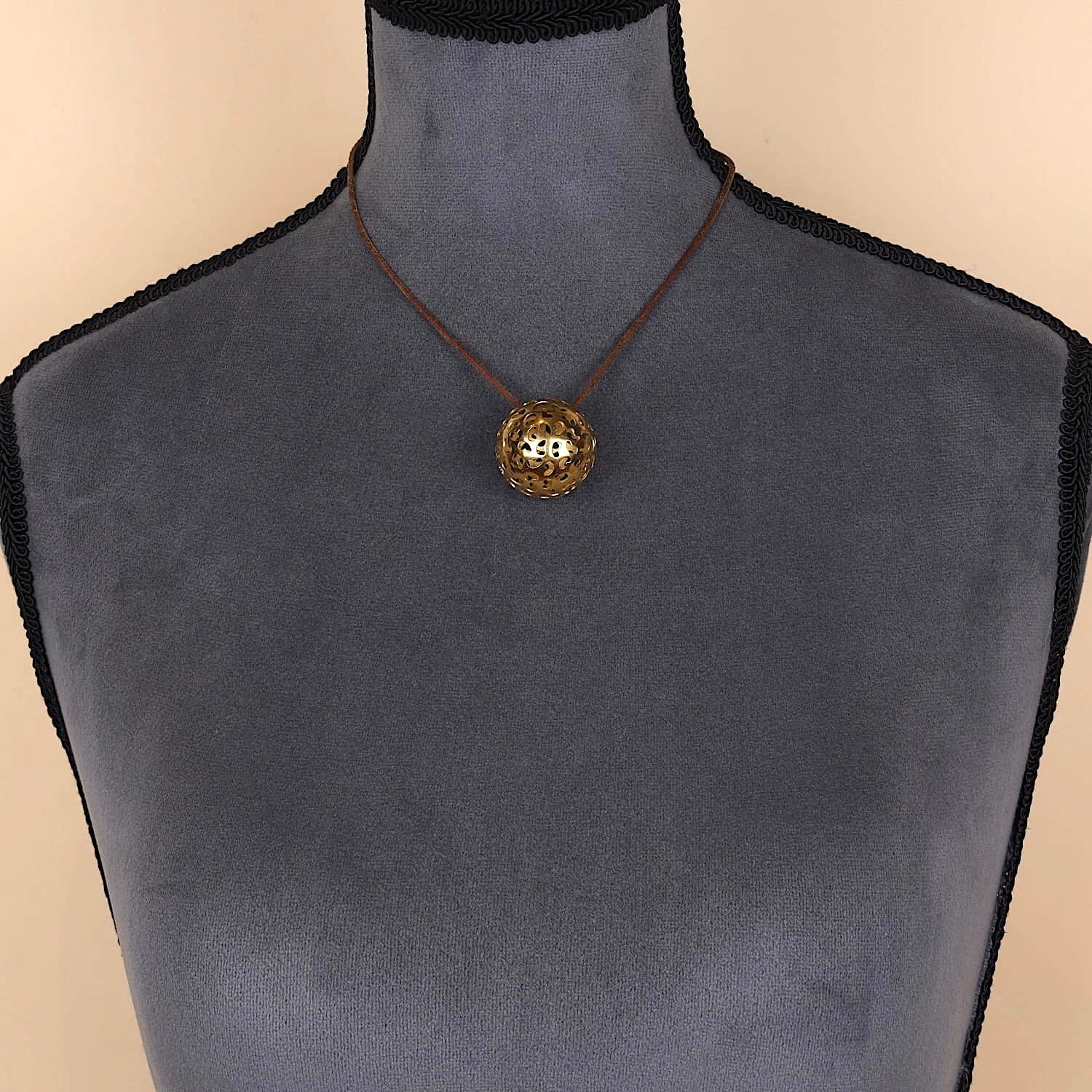 Niessing pendant in the shape of a ball made of 750 yellow gold, on a dark bust