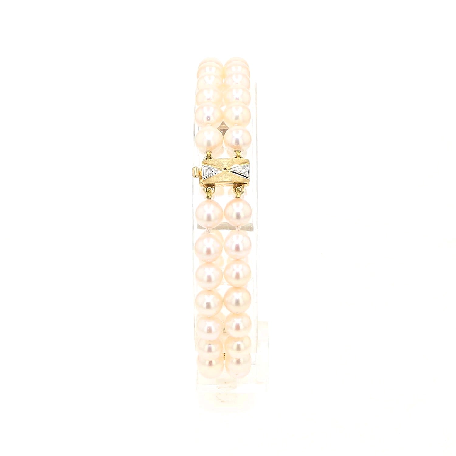 Akoya-Zuchtperlenarmband in zwei Reihen mit einem Schloss und Goldelementen aus 585er Gelbgold mit Diamanten, stehend auf einem Halter aus Kunststoff 