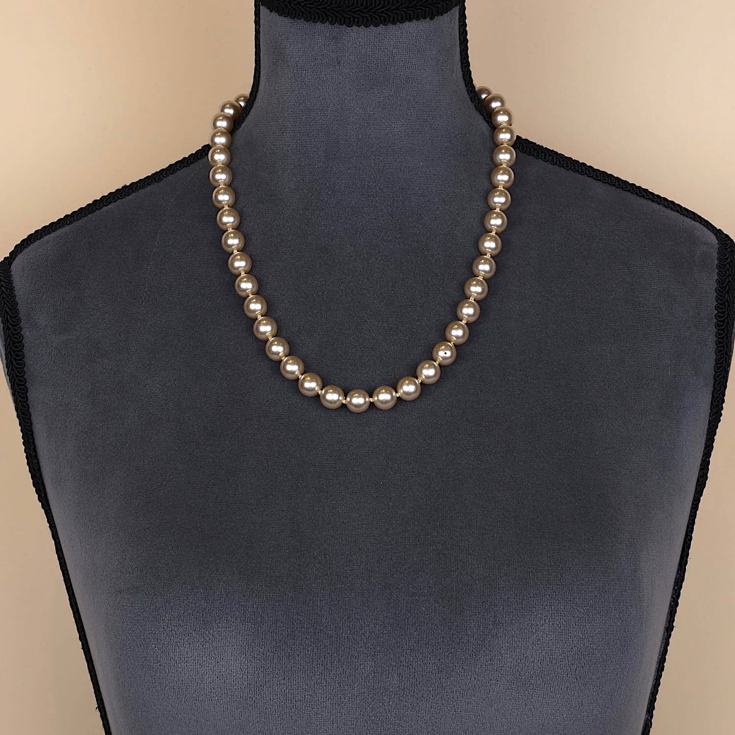 Shell bead necklace with gold-colored beads and a magnetic lock made of 585 yellow and white gold, on a dark bust